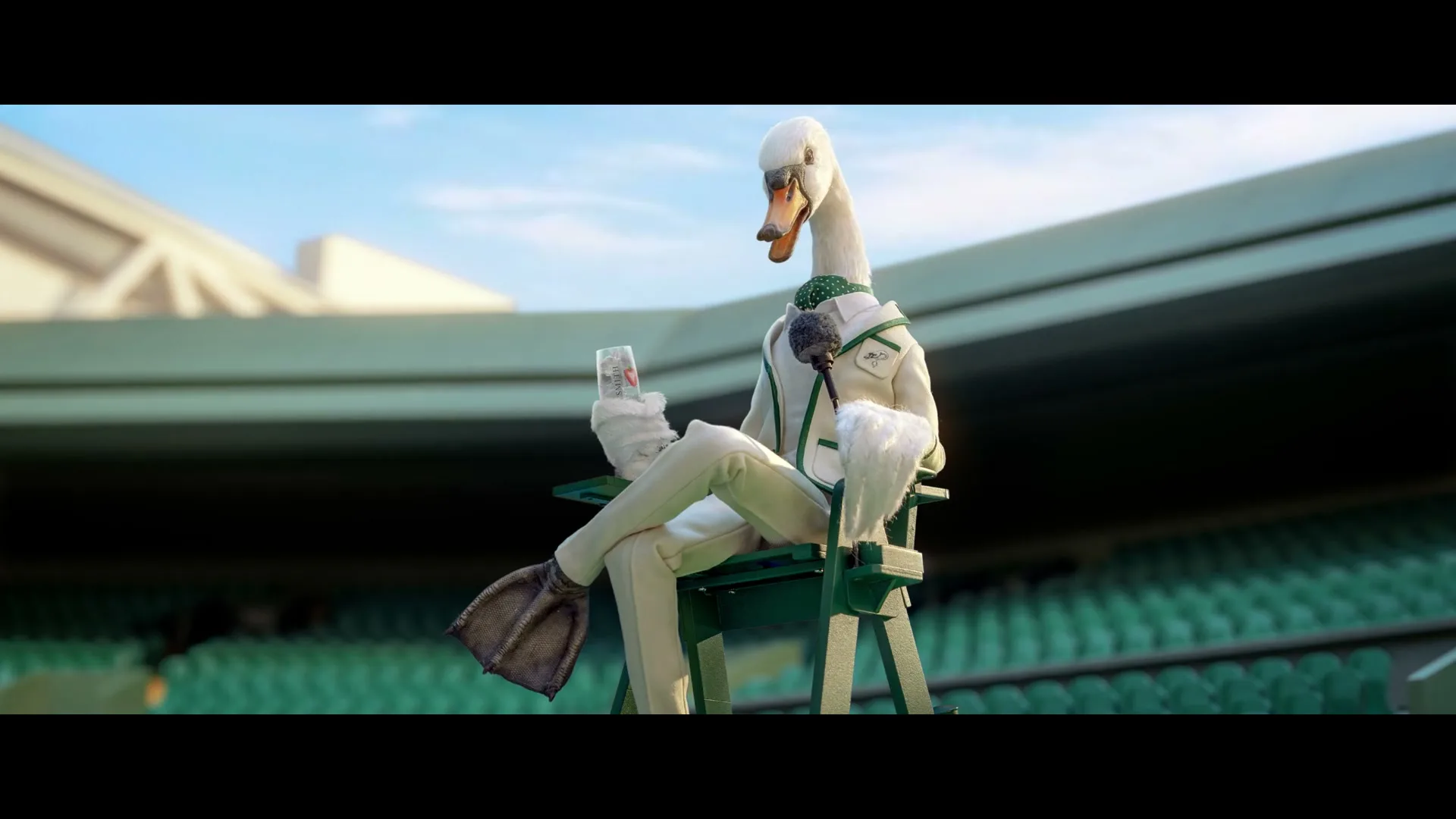 A swan-like creature, dressed in a white suit with green accents, sits on a high chair at a tennis court, holding a drink and a microphone.