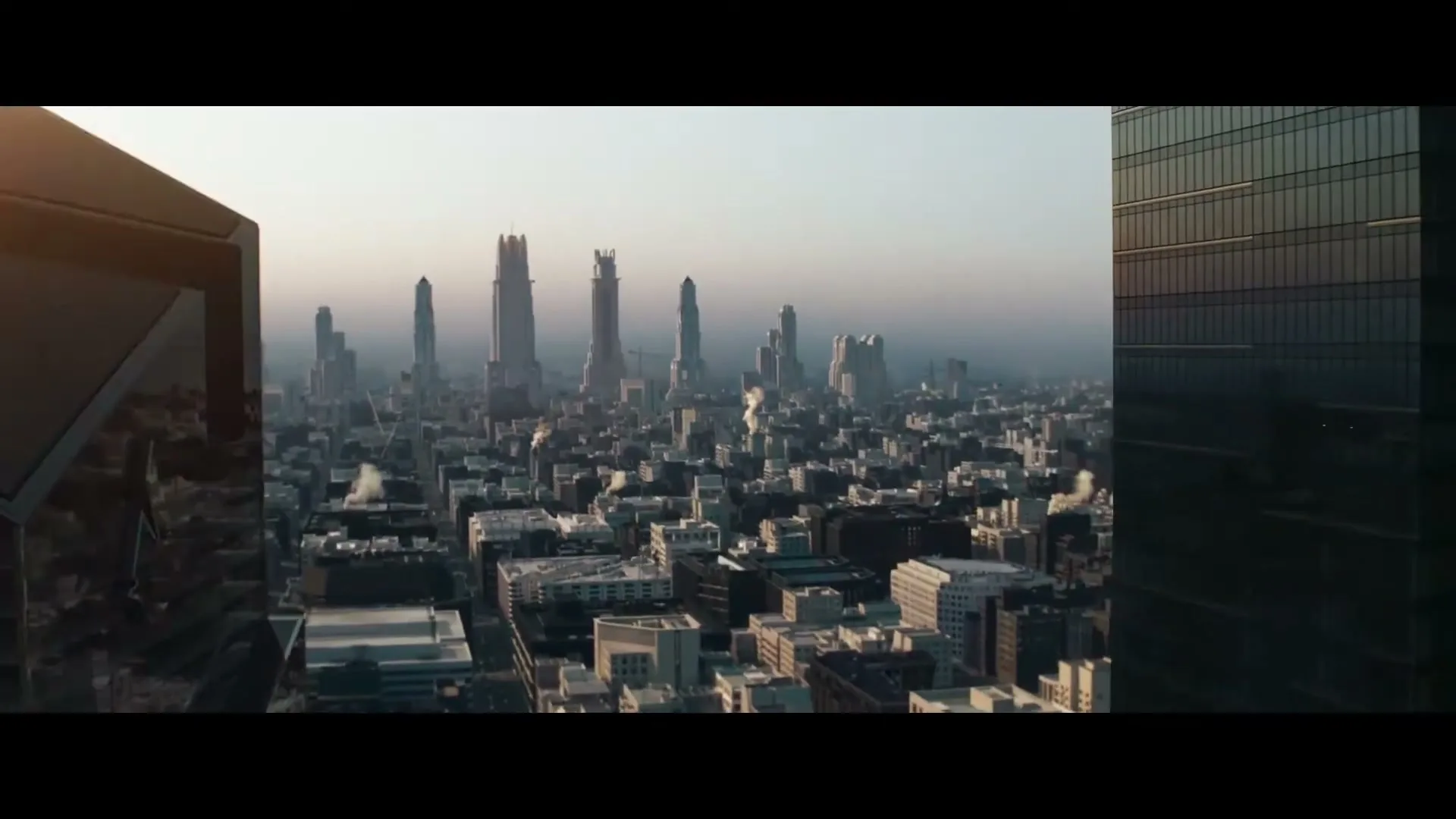An aerial view of a futuristic city with tall, unique skyscrapers and a sprawling urban landscape under a hazy sky.