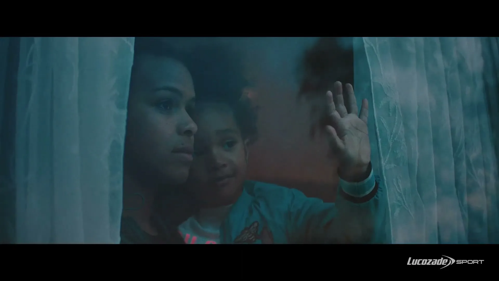 A woman and a young child look out a window, with the child's hand pressed against the glass, framed by sheer curtains.