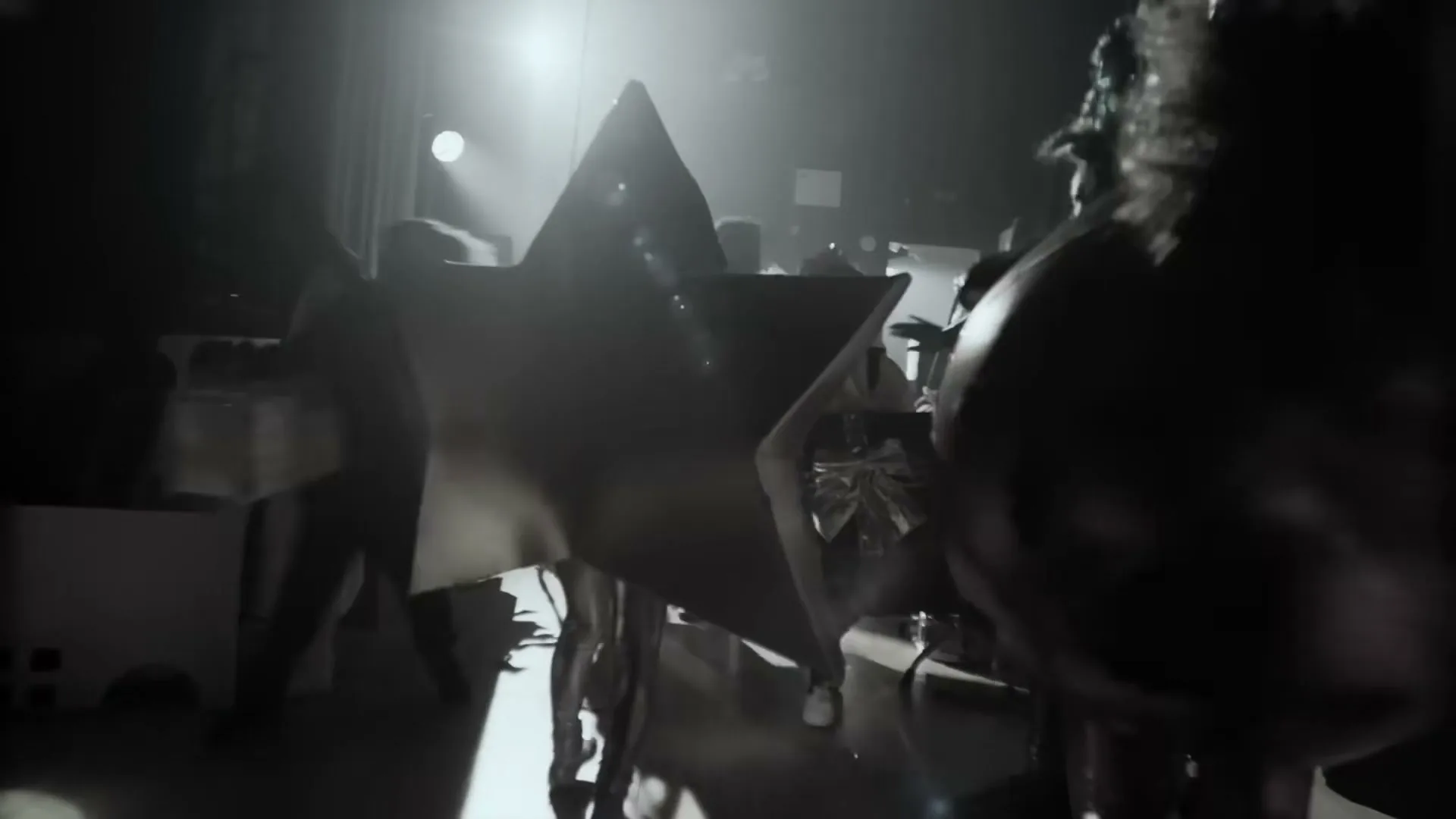 A group of children in homemade costumes, including a large star, move backstage in a dimly lit school hall.