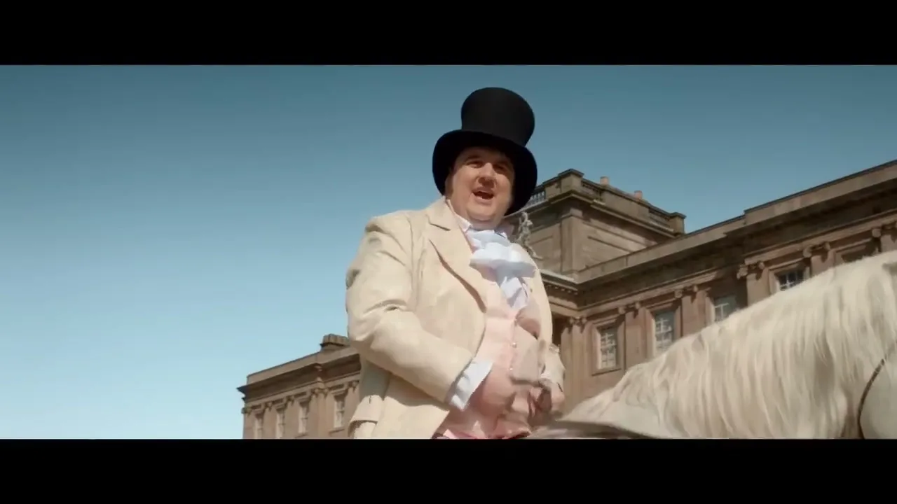 A portly man in period costume and a top hat rides a white horse past a grand stately home under a clear blue sky.