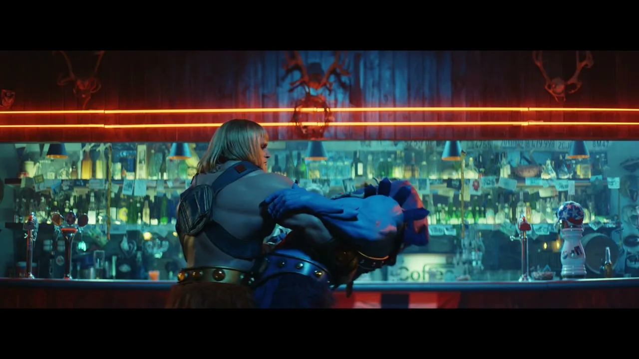 He-Man and Skeletor, dressed in their iconic costumes, dance together in a bar with neon lights and bottles in the background.