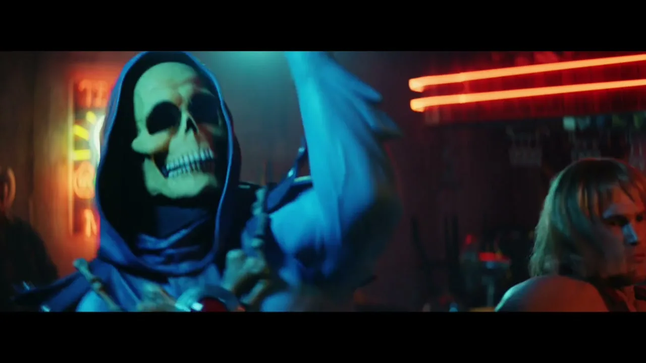 Skeletor, a skeletal figure in a blue hood and sunglasses, dances next to He-Man in a dimly lit bar with neon signs.