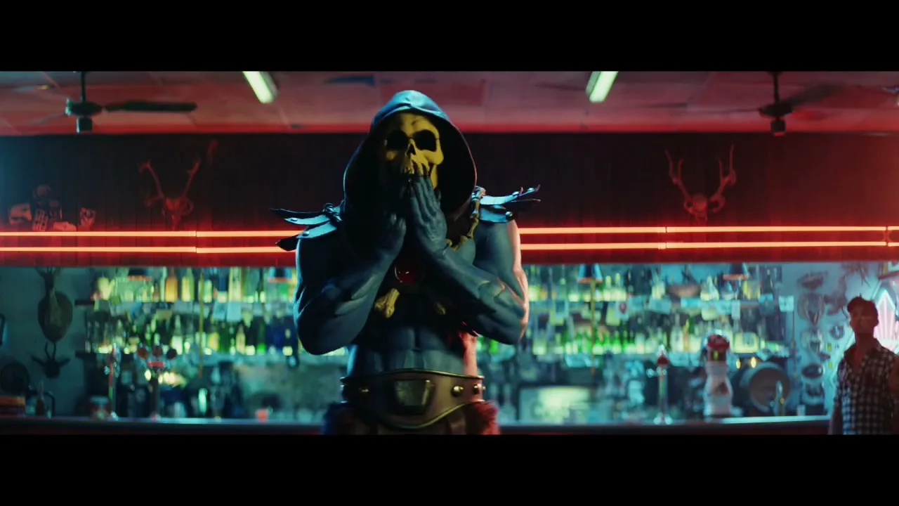 Skeletor, a muscular, blue-skinned villain with a skull face and hood, stands behind a bar, rubbing his hands together in a dimly lit bar.