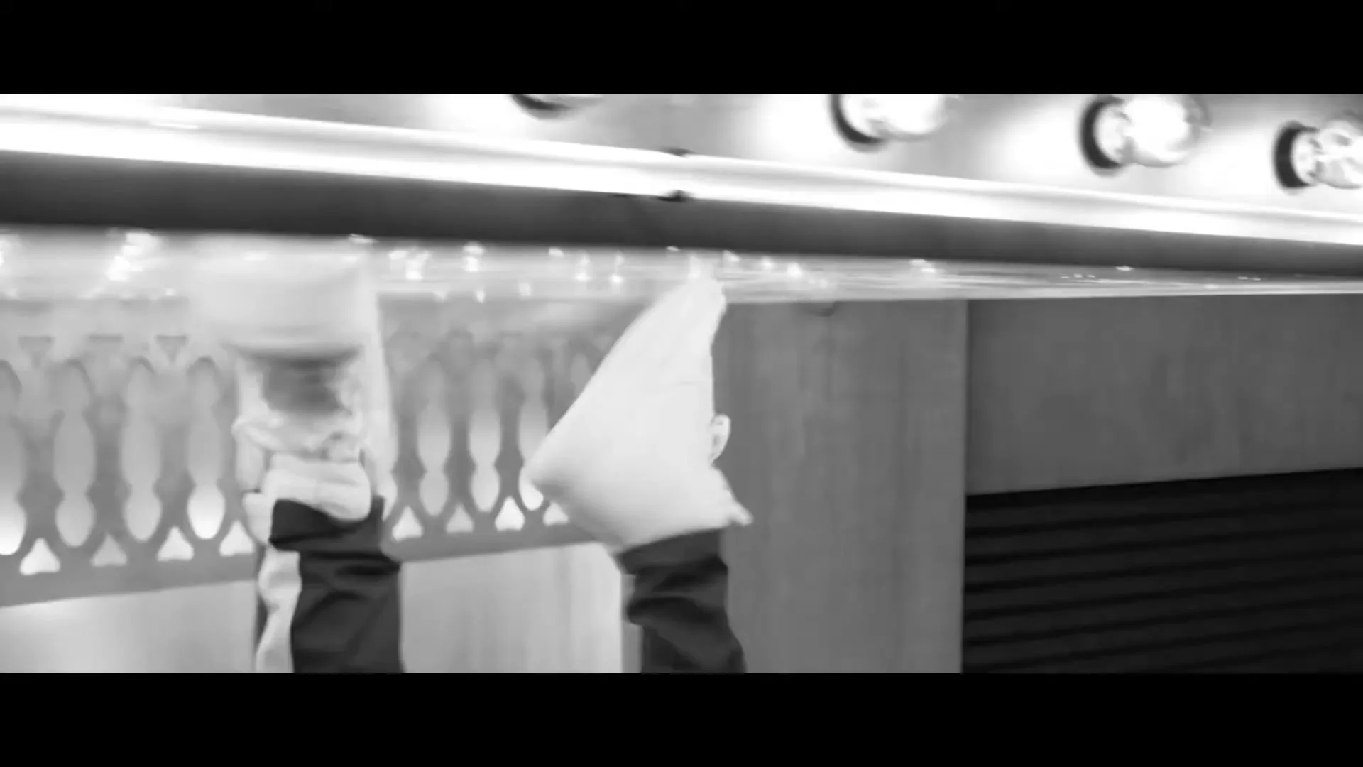 A person in white shoes and dark pants is seen upside down, walking on a ceiling in a black and white shot.