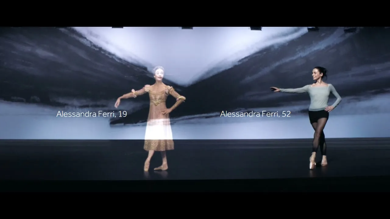 A young ballerina and an older ballerina dance in a studio with a projected abstract background, showcasing their grace and skill.
