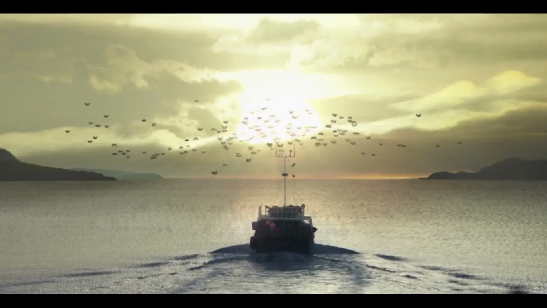 A small boat sails away from the camera into the sunset, leaving a wake behind it, with birds flying above.