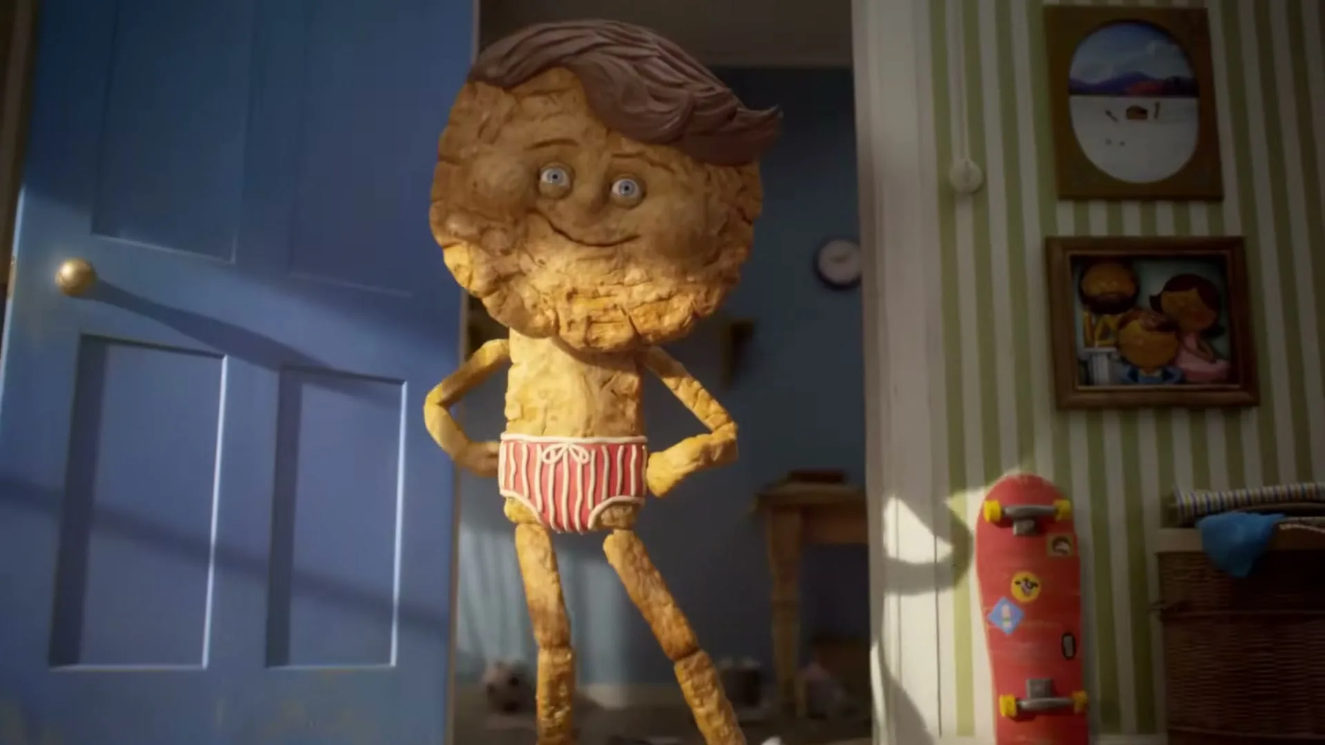 A stop-motion animated biscuit boy in red striped underwear stands in a doorway, hands on hips, in a whimsical, striped-wallpaper room.