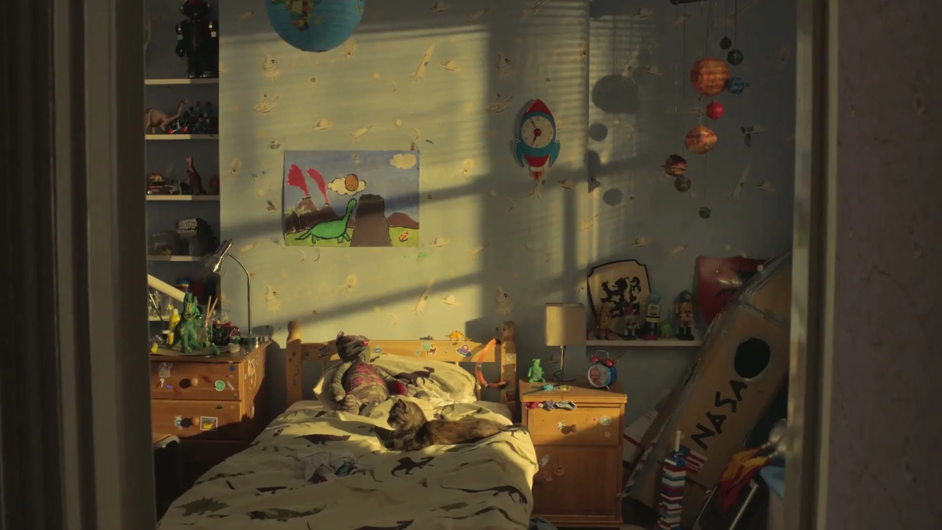 A wide shot of a child's bedroom, filled with toys and a bed, with sunlight streaming through the window.