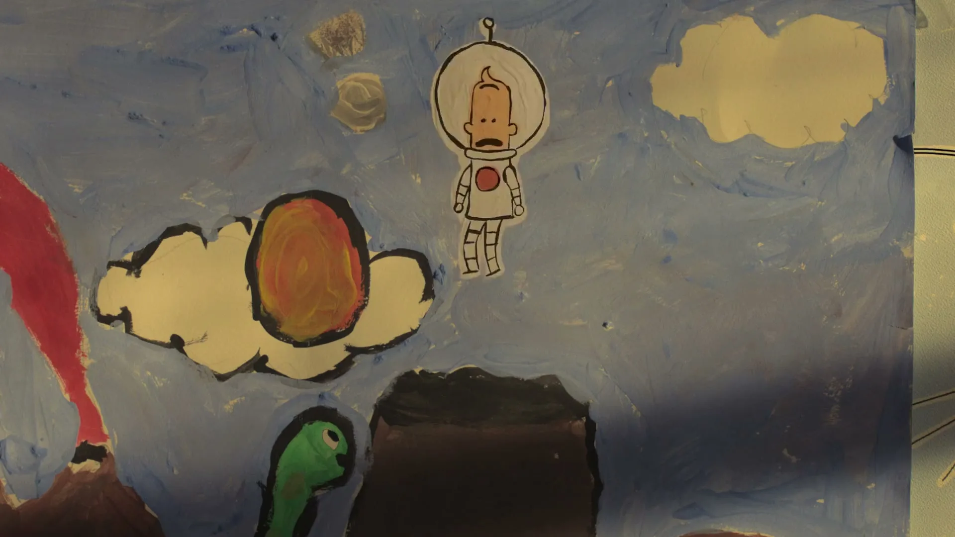 A child's drawing of a cartoon astronaut floating in a blue sky with clouds, a volcano, and a green creature, as the astronaut falls into a dark hole.