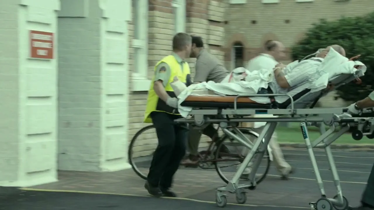 A man on a bicycle is hit by a stretcher being pushed by two paramedics, as they rush a patient into a hospital emergency entrance.