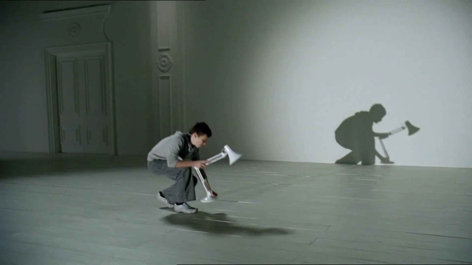 A group of people in a white room create shadows on the wall using various objects, forming a playful and imaginative scene.