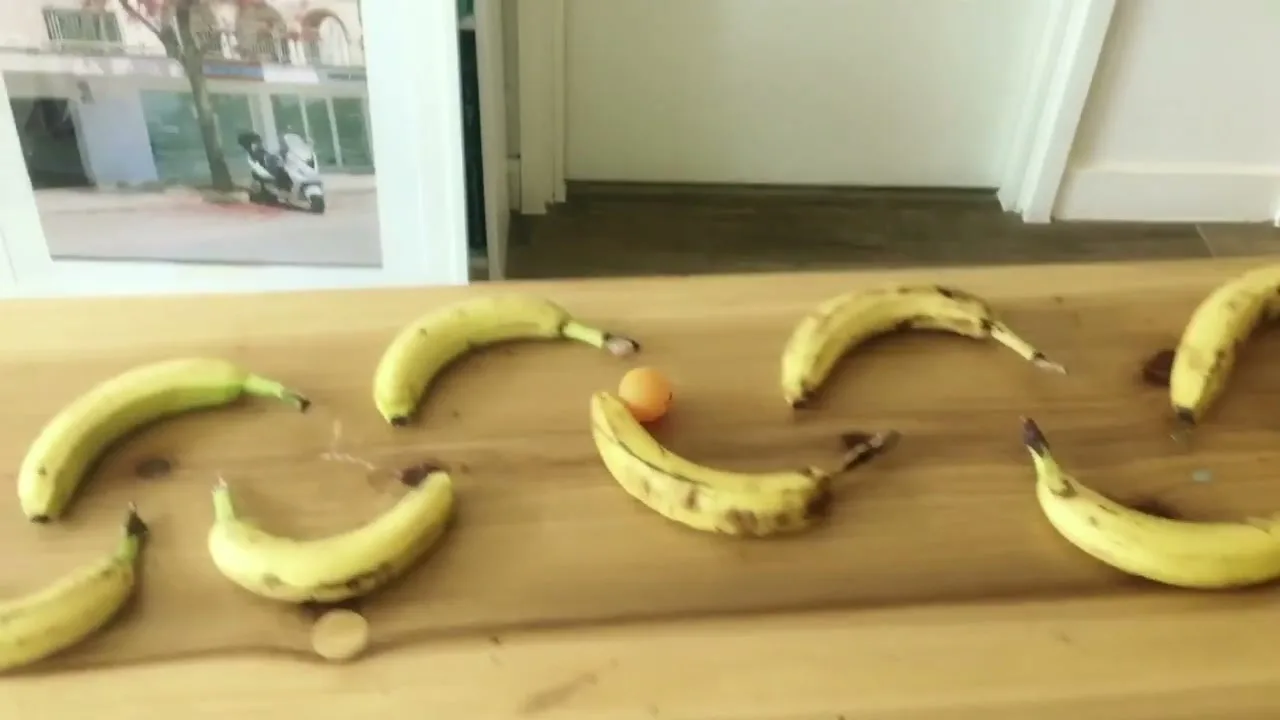 A hand pushes a small red wheel, starting a chain reaction of household objects, including dominoes, bananas, and a toy car, culminating in a Honda banner unfurling.