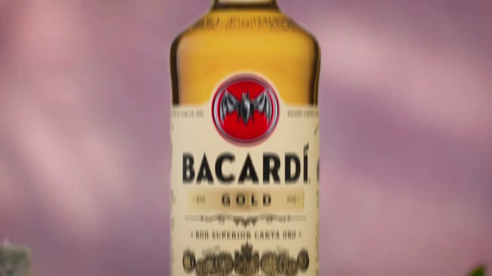 A close-up shot of a Bacardi Gold Rum bottle, with its label and golden liquid clearly visible against a soft, blurred background.