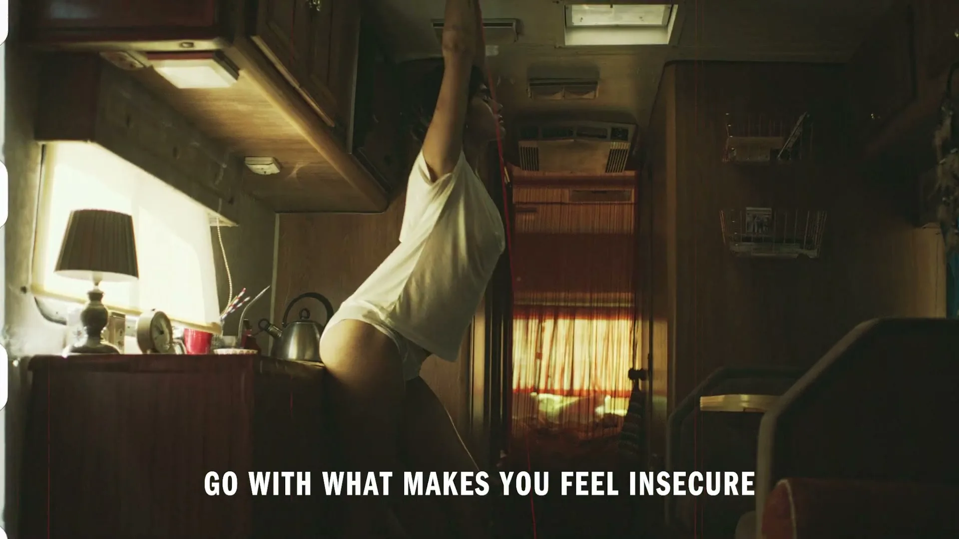 A young woman in a white t-shirt and underwear stretches inside a vintage camper van, with text overlay.