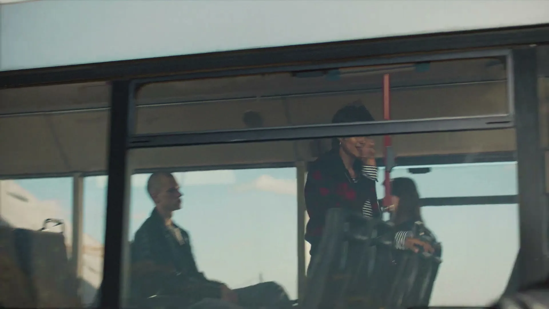 A diverse group of young people with alternative styles are riding a bus, looking out the window as the bus moves.