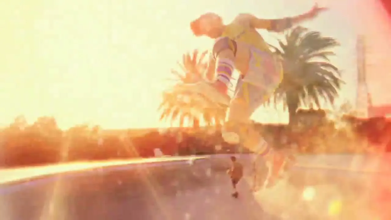 A male skateboarder in a yellow shirt and colorful pants performs a trick in a sun-drenched skate park with palm trees in the background.