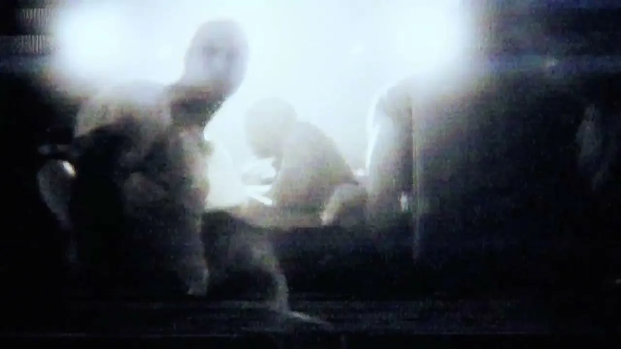 A group of people are silhouetted against a bright, overexposed light source, creating a dramatic and mysterious scene in a dark interior.