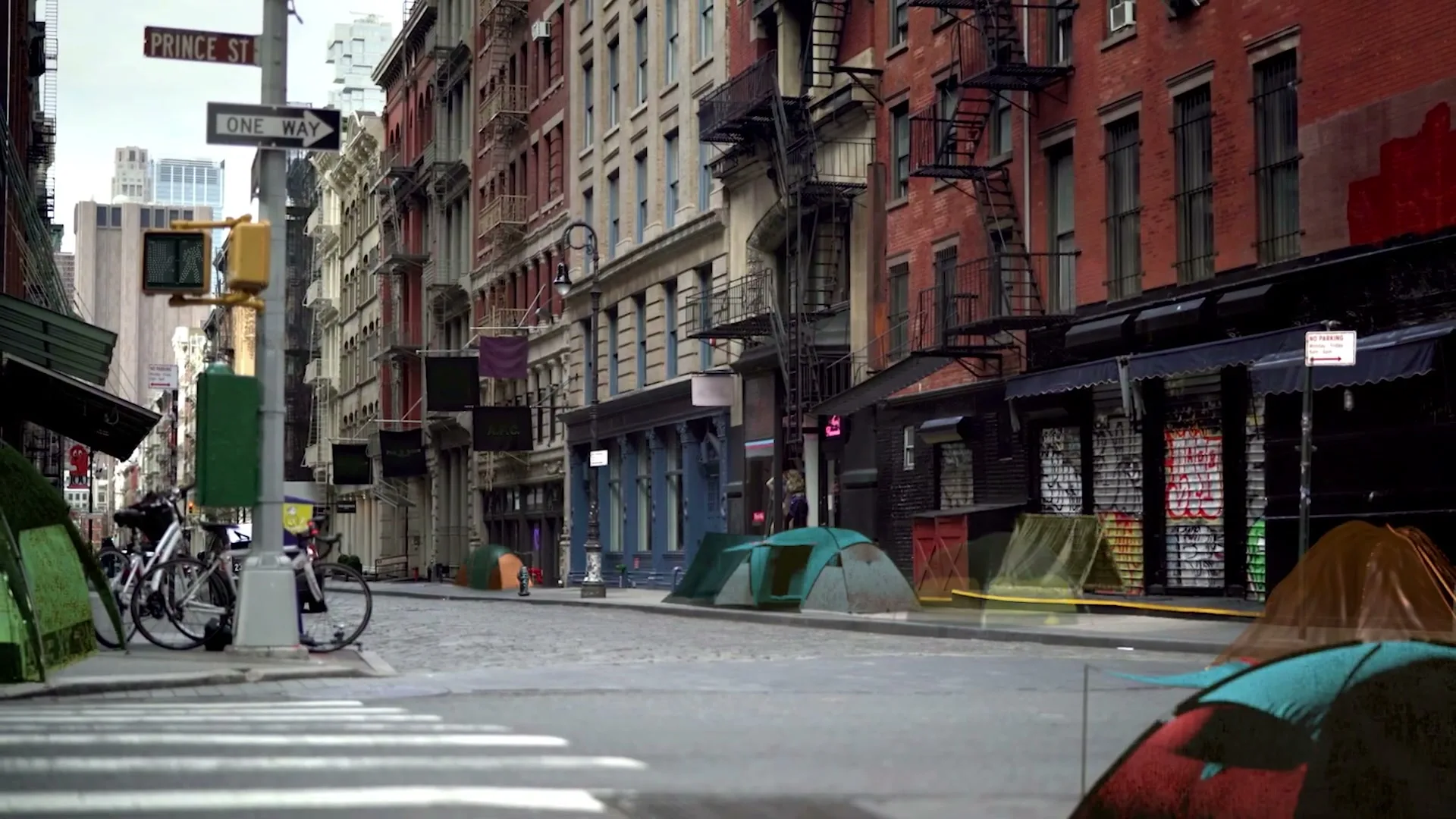 An empty city street with brick buildings and fire escapes slowly fills with colorful tents, suggesting a growing homeless encampment.