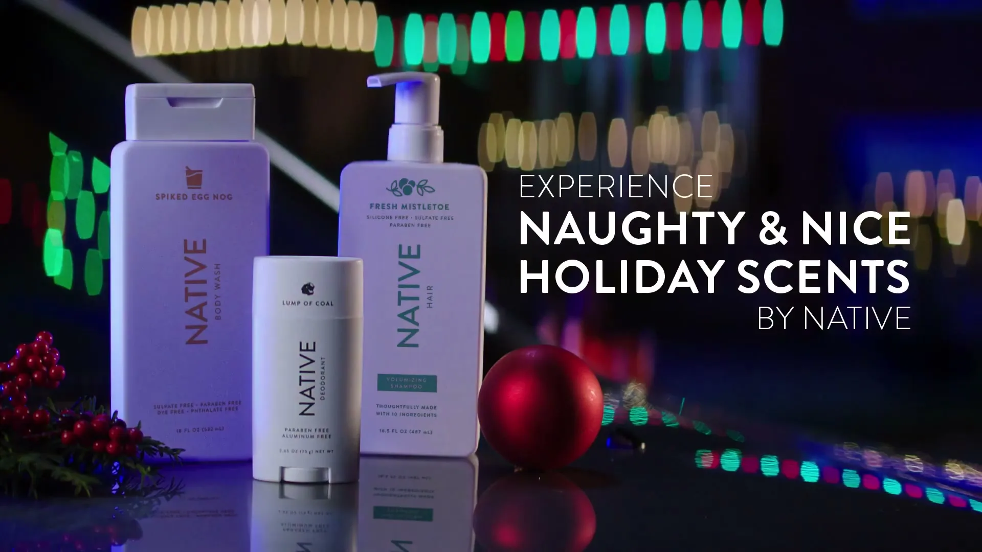 Three Native brand holiday-themed personal care products are displayed on a reflective surface with festive lights in the background and text overlay.