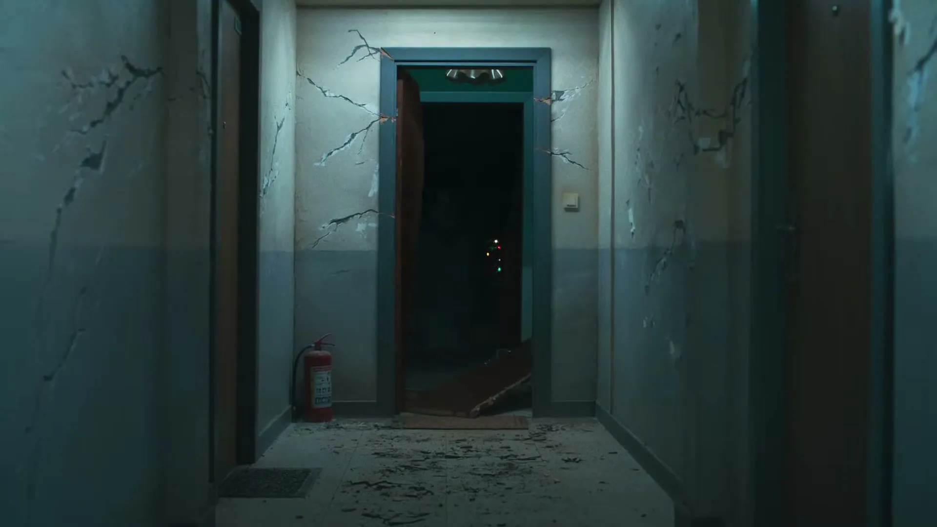 A dark, dilapidated apartment hallway with cracked walls and debris on the floor, as a door at the end of the hall is violently ripped open.