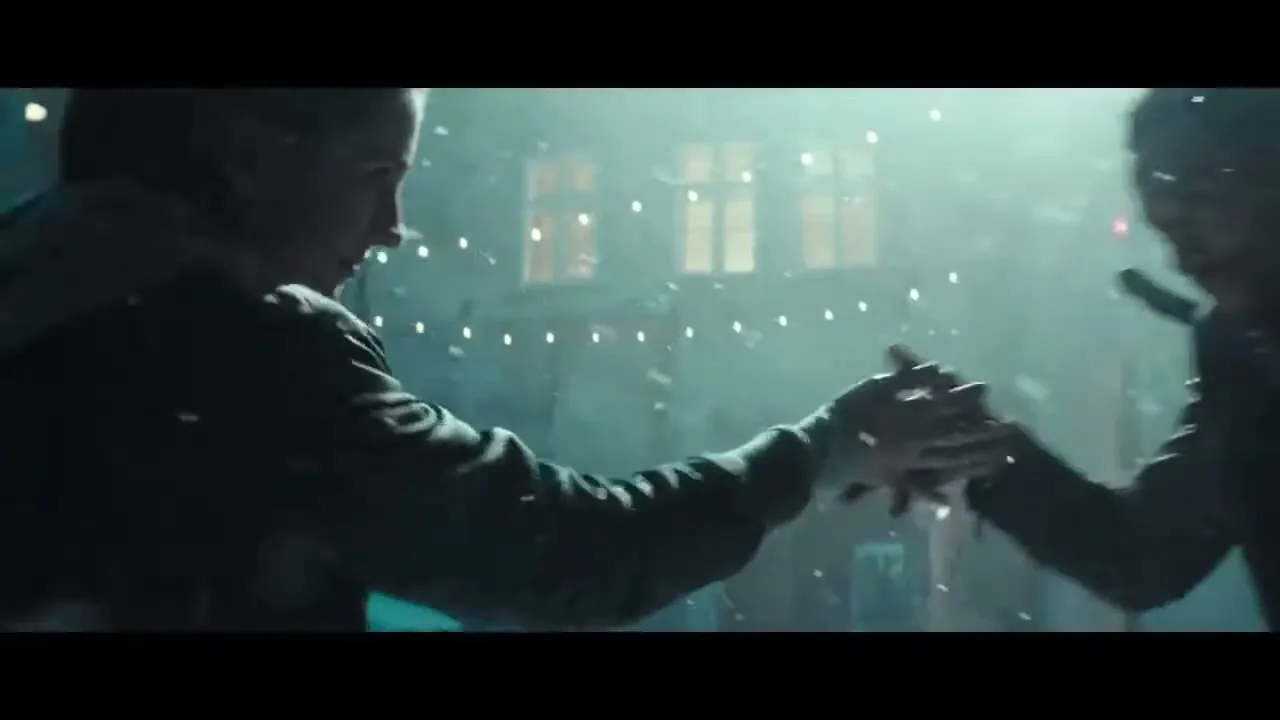 A man and a woman dance closely, holding hands and looking at each other, in a snowy, dimly lit city street at night.