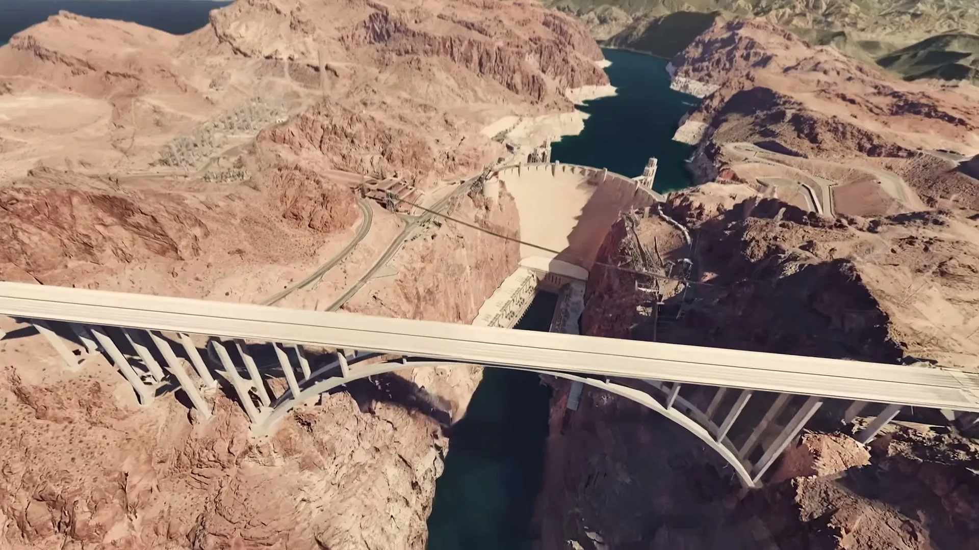 An aerial view of the Hoover Dam and the Mike O'Callaghan – Pat Tillman Memorial Bridge, with the camera moving down towards the dam.