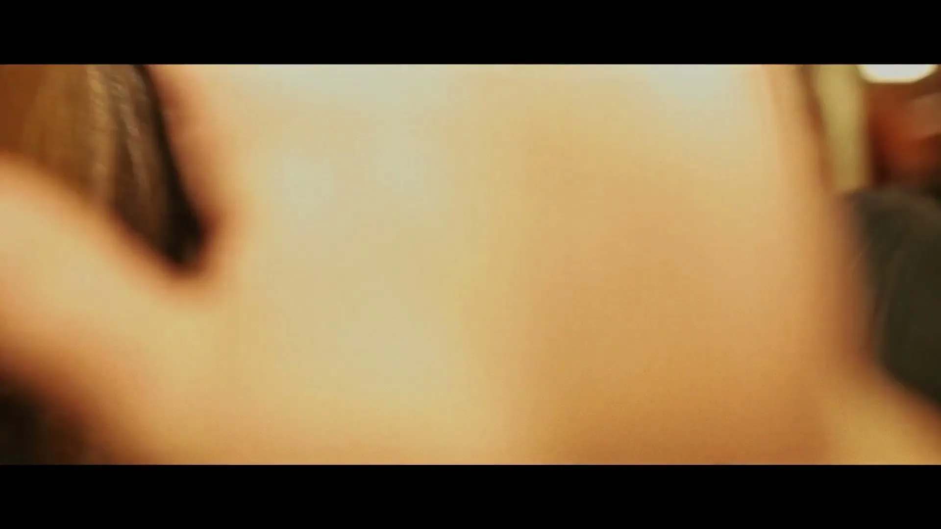 A young woman with long blonde hair has her face partially obscured by a hand, while another woman is out of focus in the background.