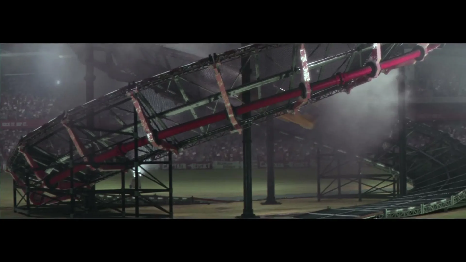 A yellow car slides down a large, curved metal ramp in a stadium, with smoke and mist around it.