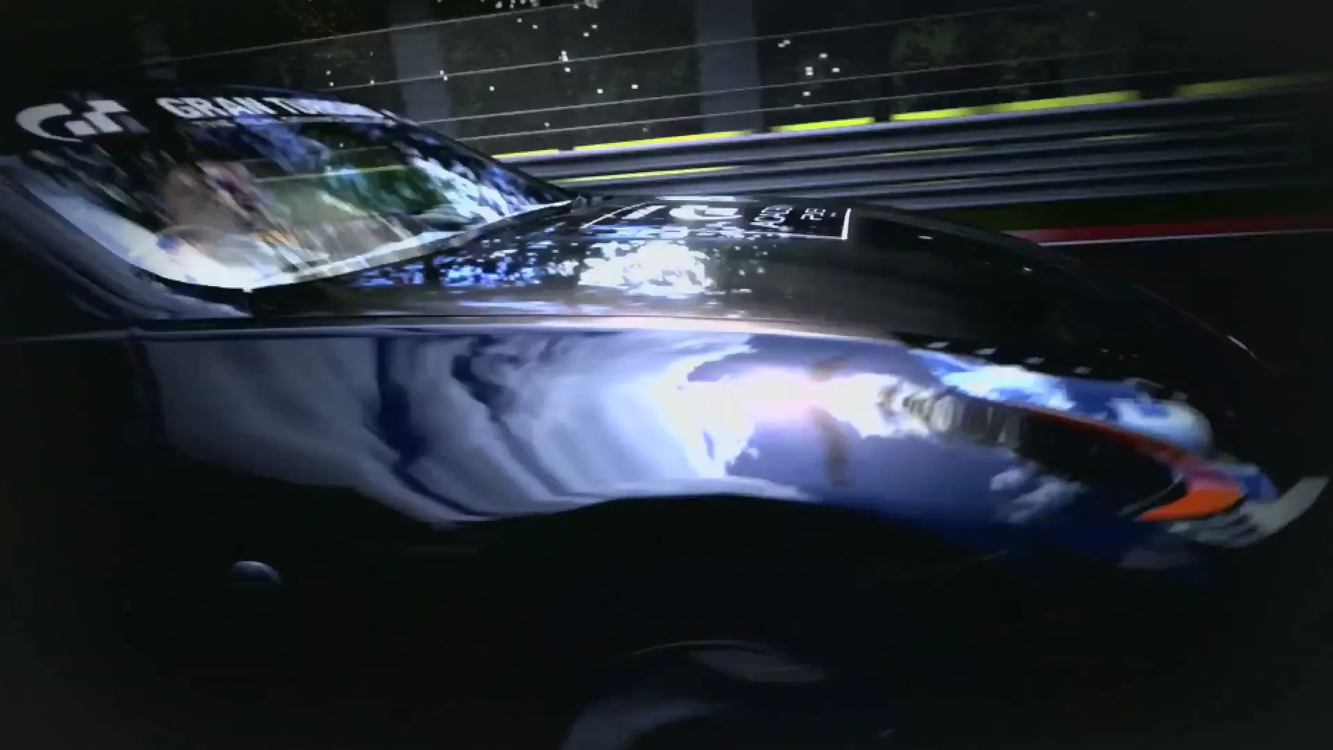 A black Nissan sports car with "Nissan GT Academy" branding on its side and hood races on a track, with a red car visible in the background.