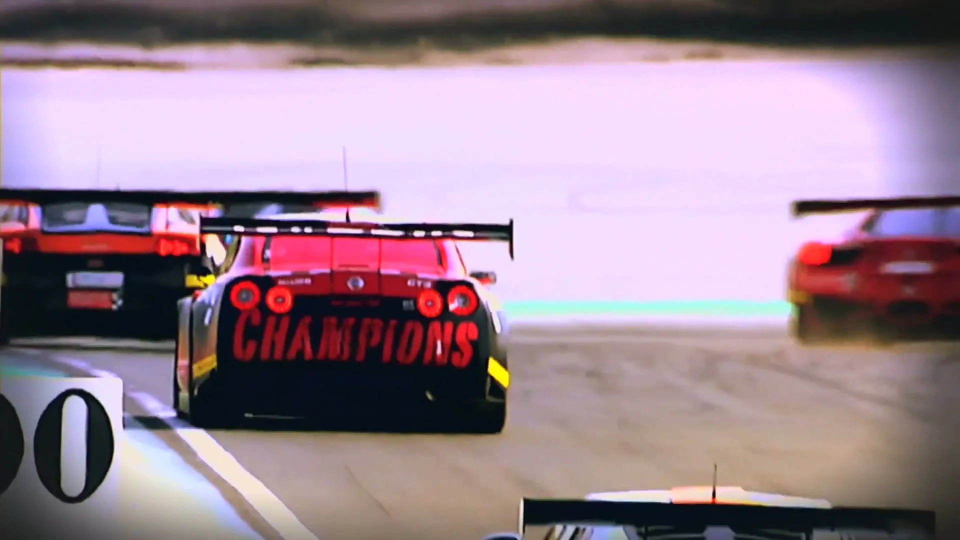 Three race cars speed around a track, with one red and black car prominently displaying "CHAMPIONS" on its rear.