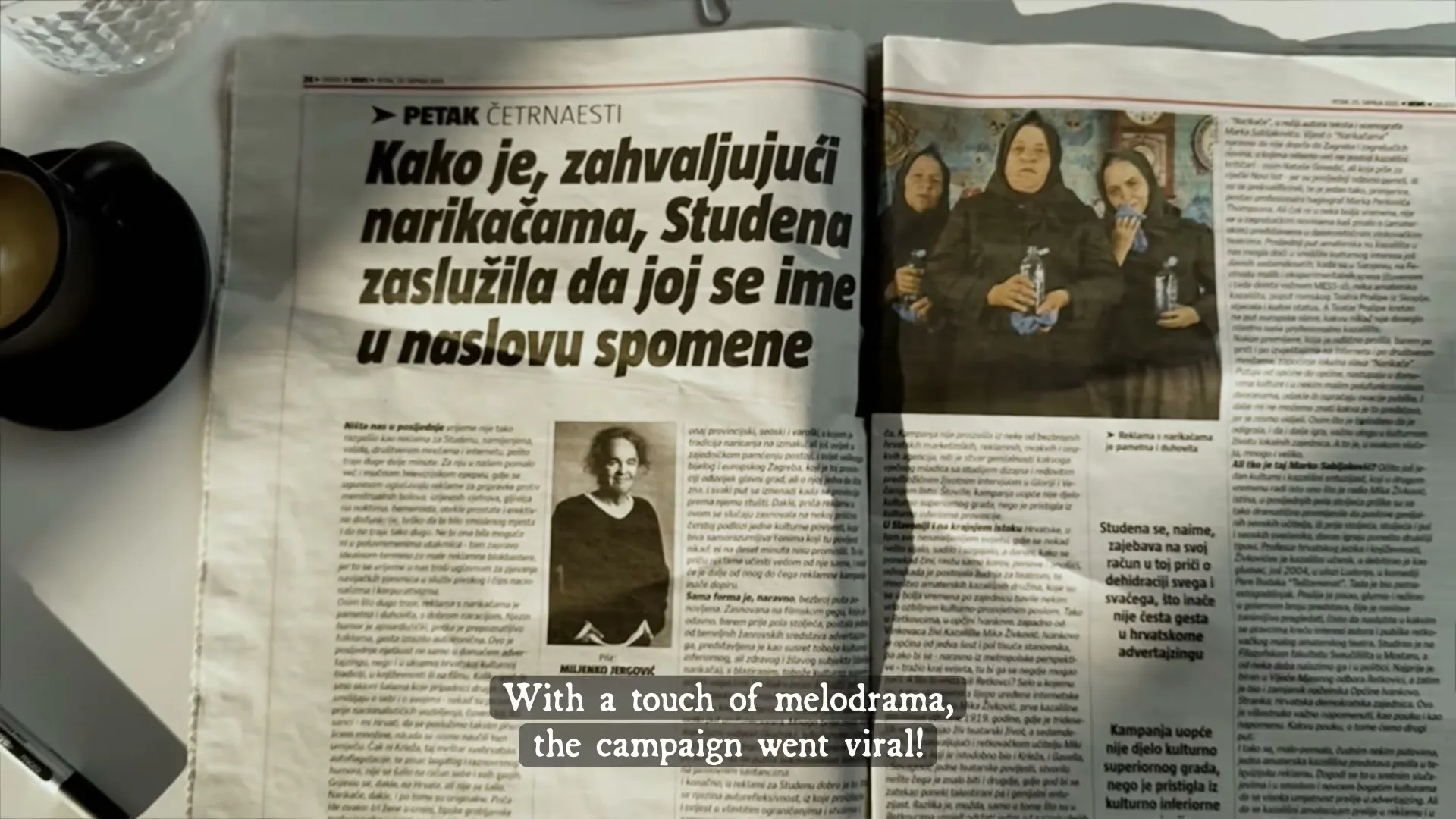 A newspaper spread with a headline about Studena and an image of three women in black dresses holding water bottles, with a coffee cup and pen on the table.