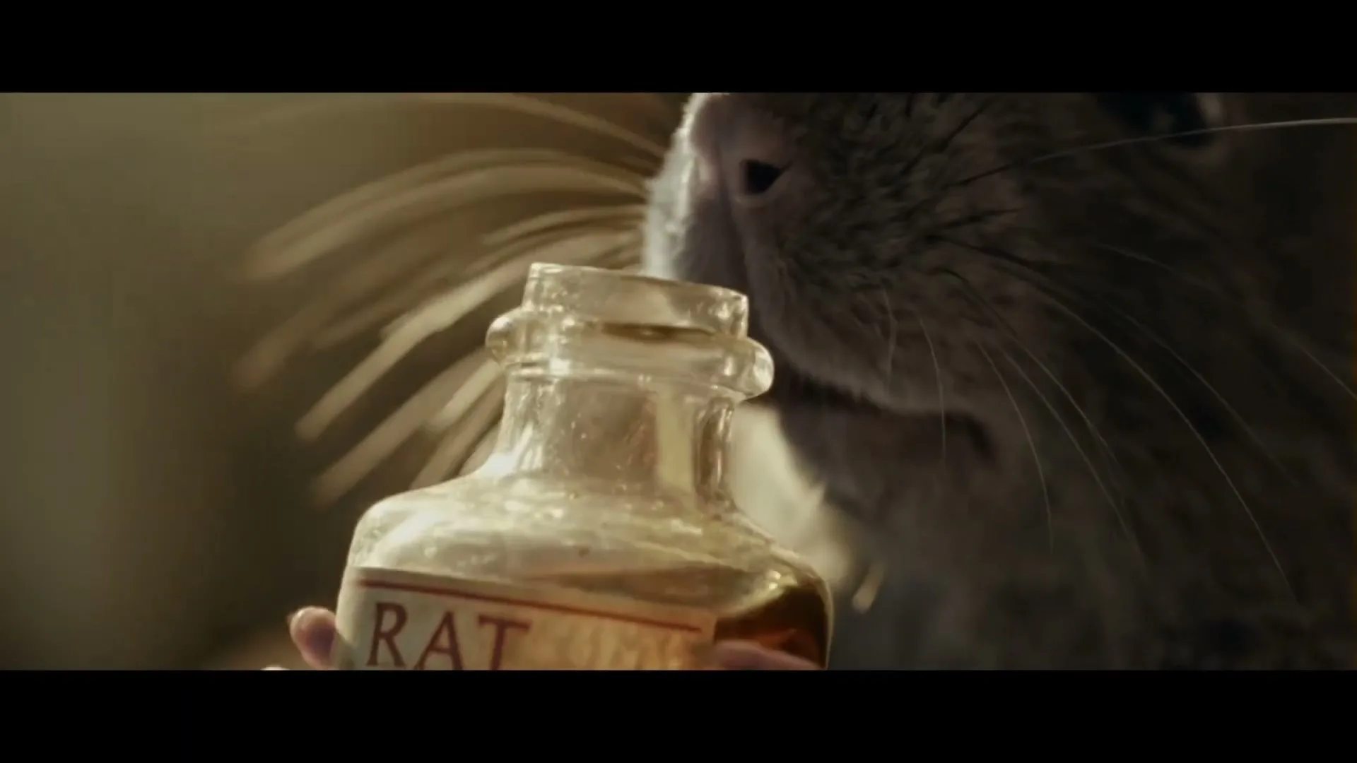 A close-up shot shows a rat holding a small bottle labeled "RAT" with a skull and crossbones, sniffing its contents.