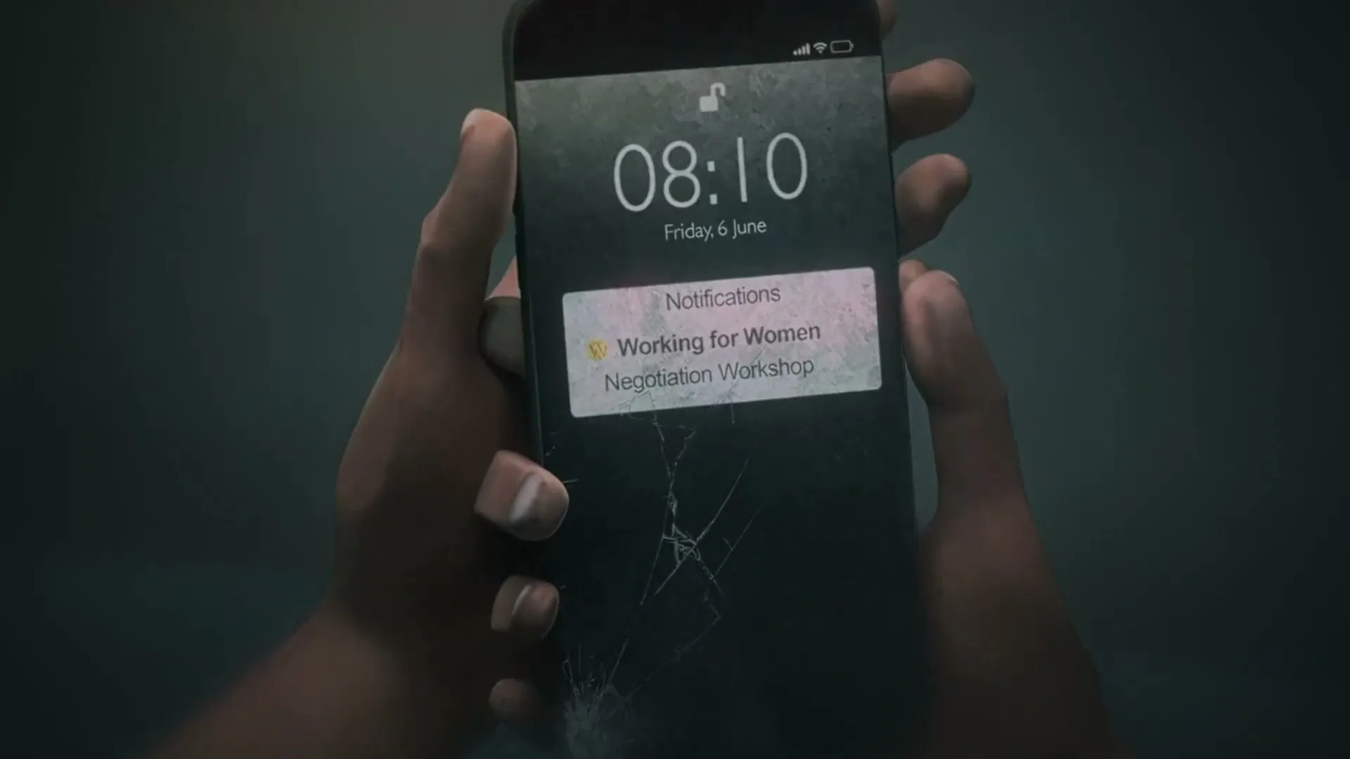 A person's hands hold a smartphone with a cracked screen, displaying a notification for a "Working for Women Negotiation Workshop" at 08:10 on Friday, June 6.