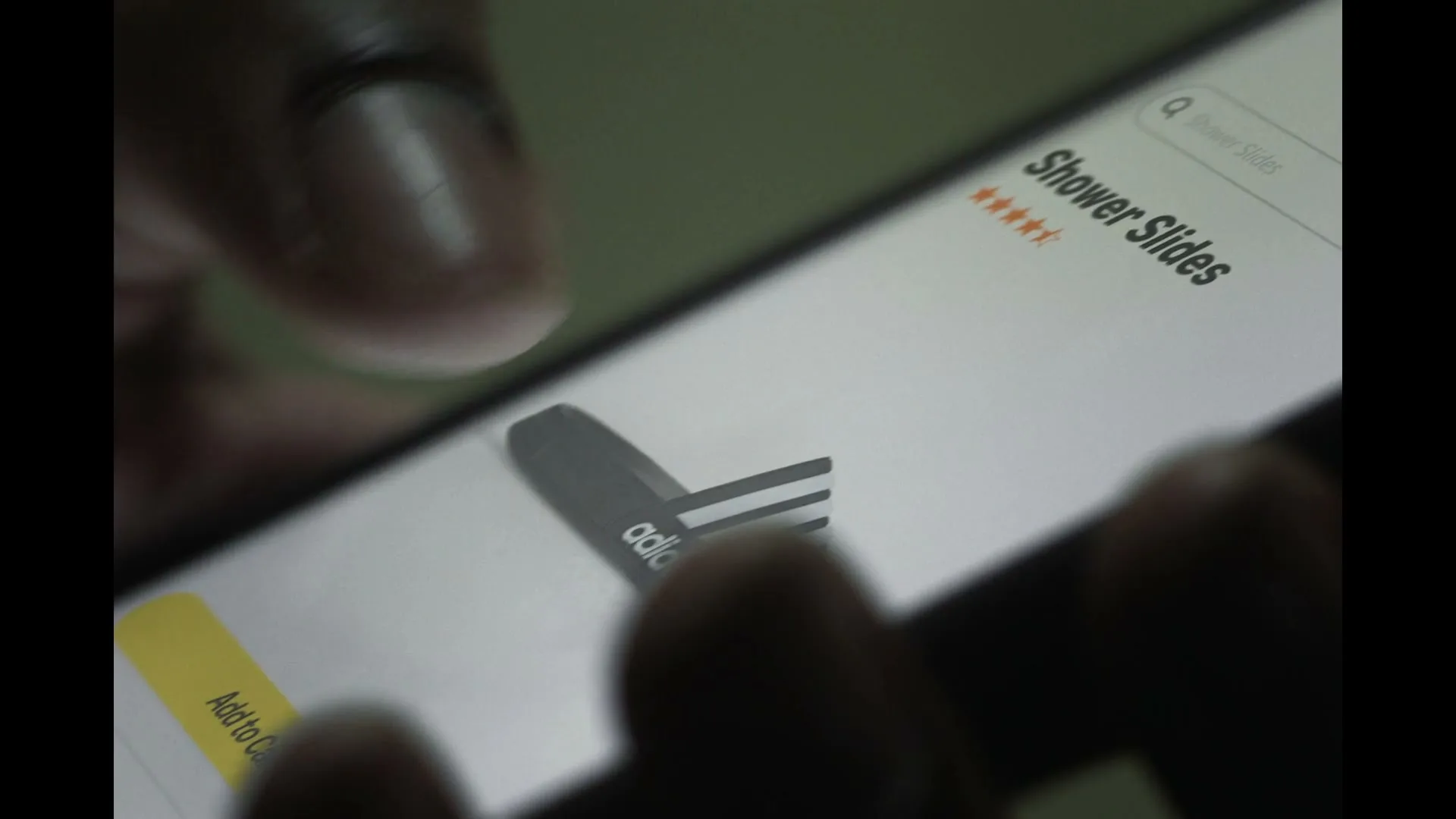 A person's fingers scroll on a smartphone screen displaying "Shower Slides" and an Adidas shower slide product page.