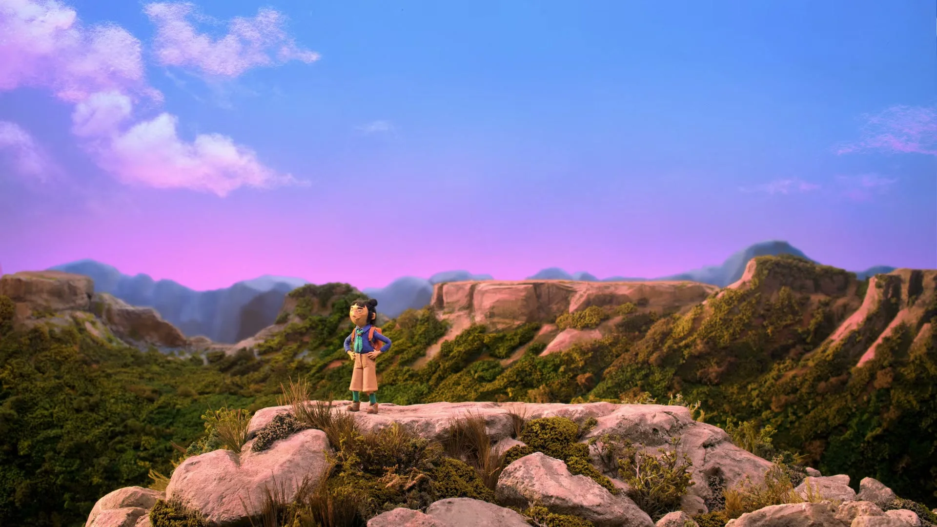 A stop-motion animated hiker stands on a rocky outcrop, looking out over a vast, green valley under a vibrant purple and blue sky.