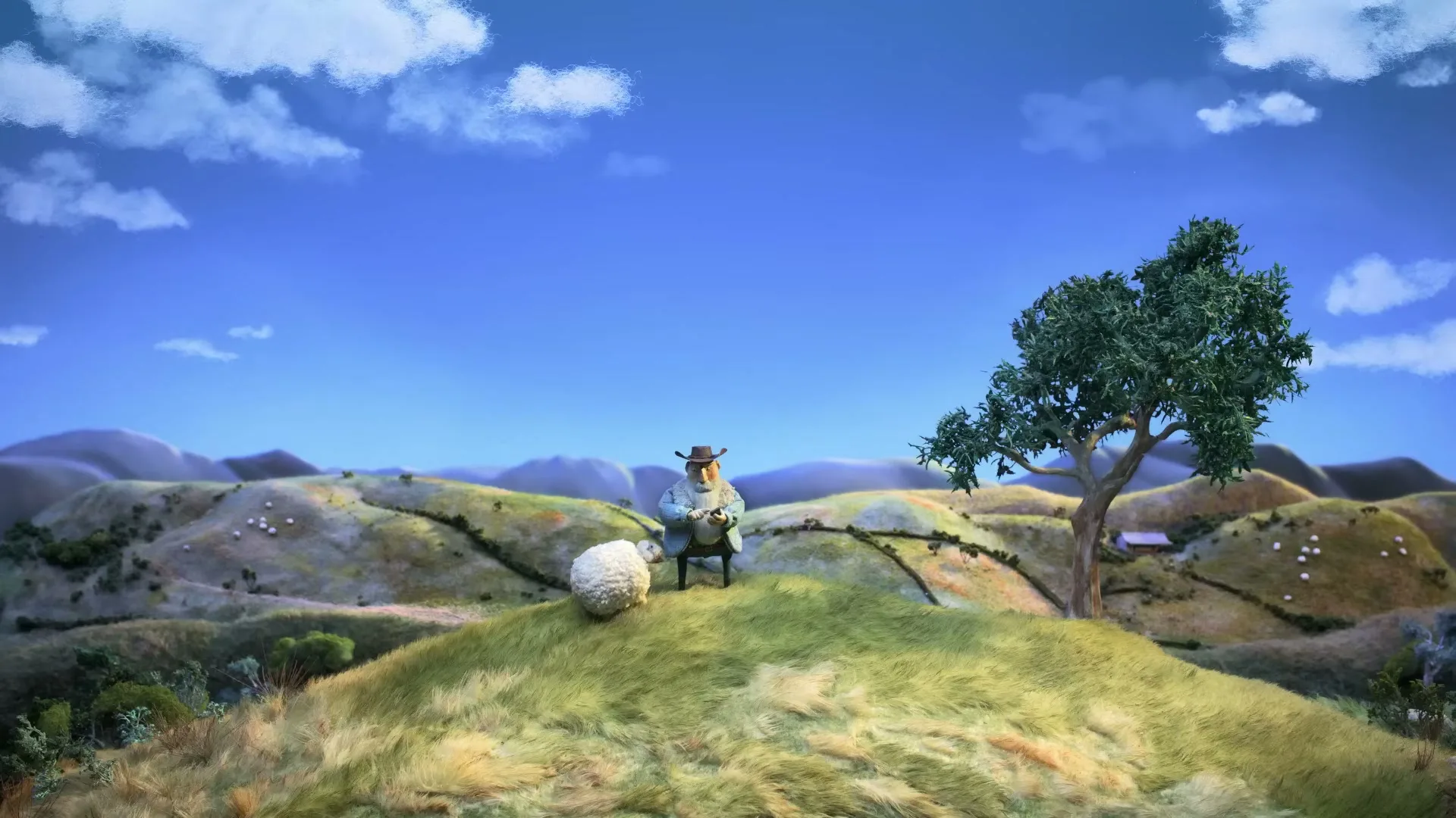 A claymation farmer sits on a grassy hill with a sheep, overlooking a vast, hilly landscape under a bright blue sky.