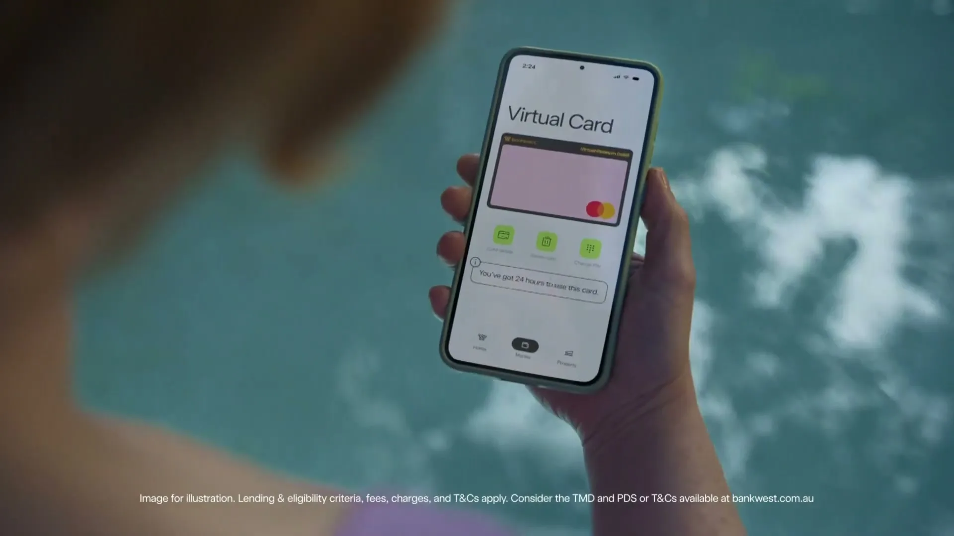 A person holds a smartphone displaying a "Virtual Card" interface, with a pink card and green icons, while submerged in water.
