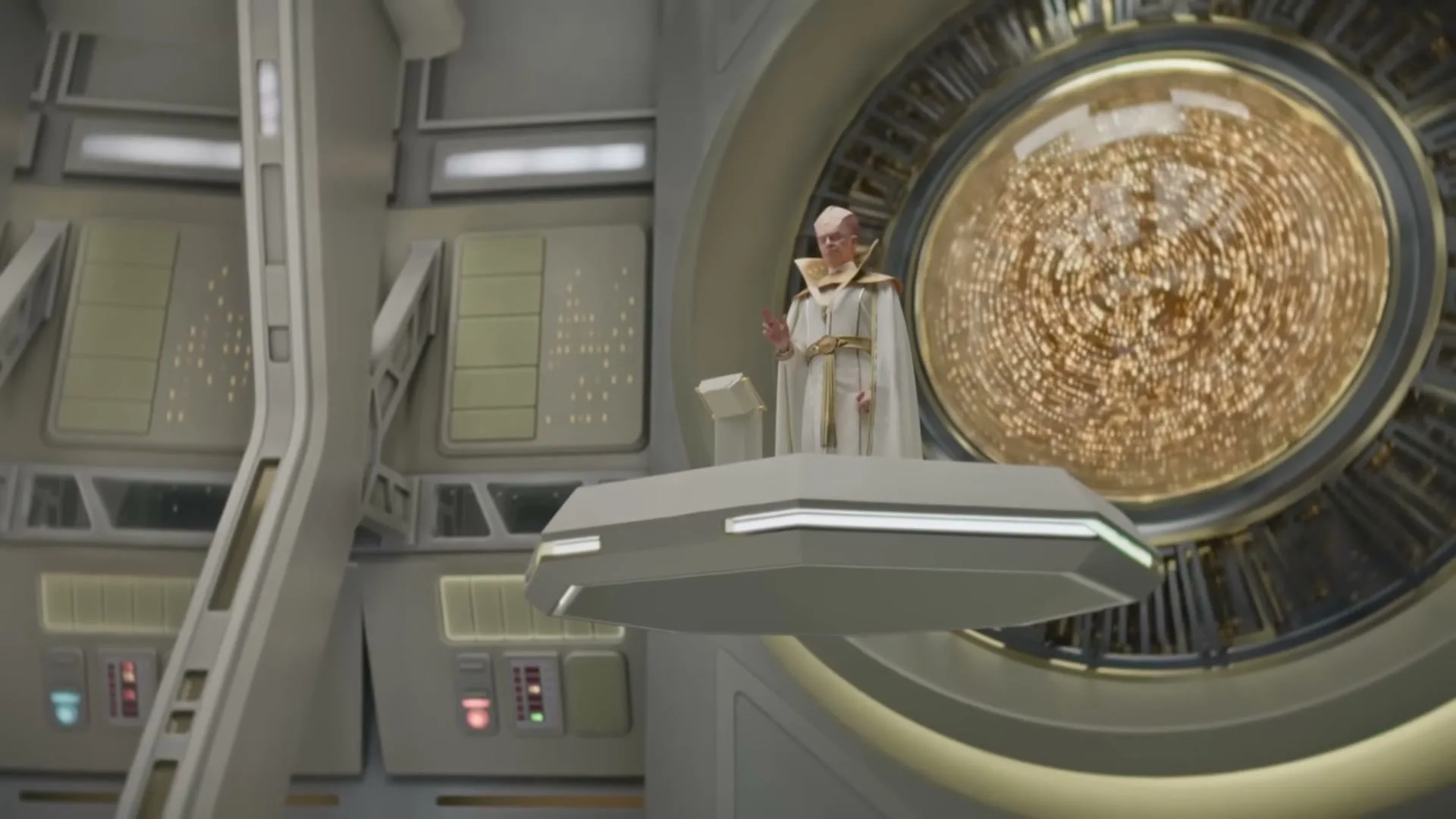 An alien leader in a white and gold robe stands on a floating platform, addressing an unseen audience in a futuristic, sterile spaceship interior.