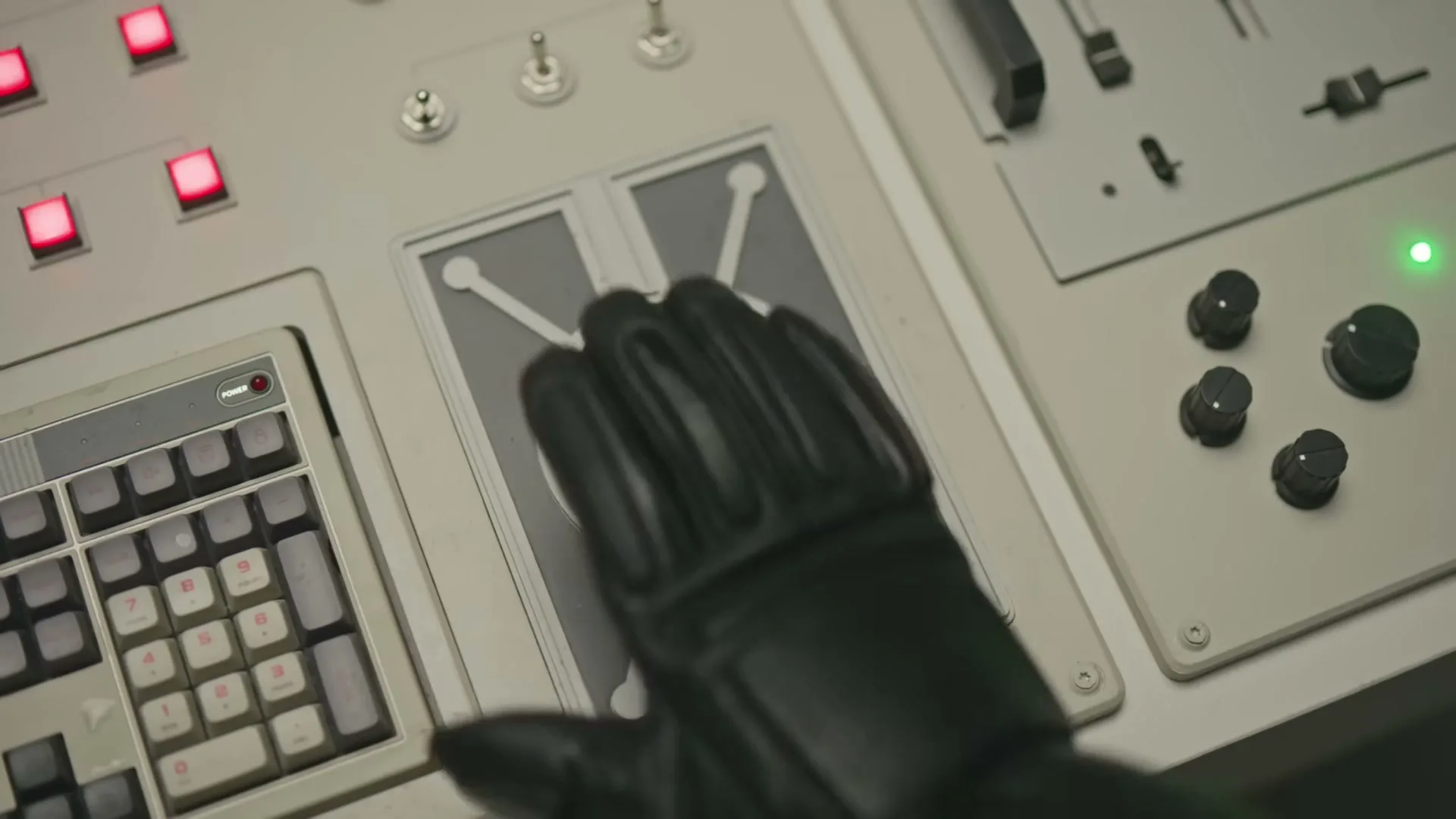 A gloved hand presses a large, round button labeled "SCAM" on a retro-futuristic control panel, causing the button to light up gold.
