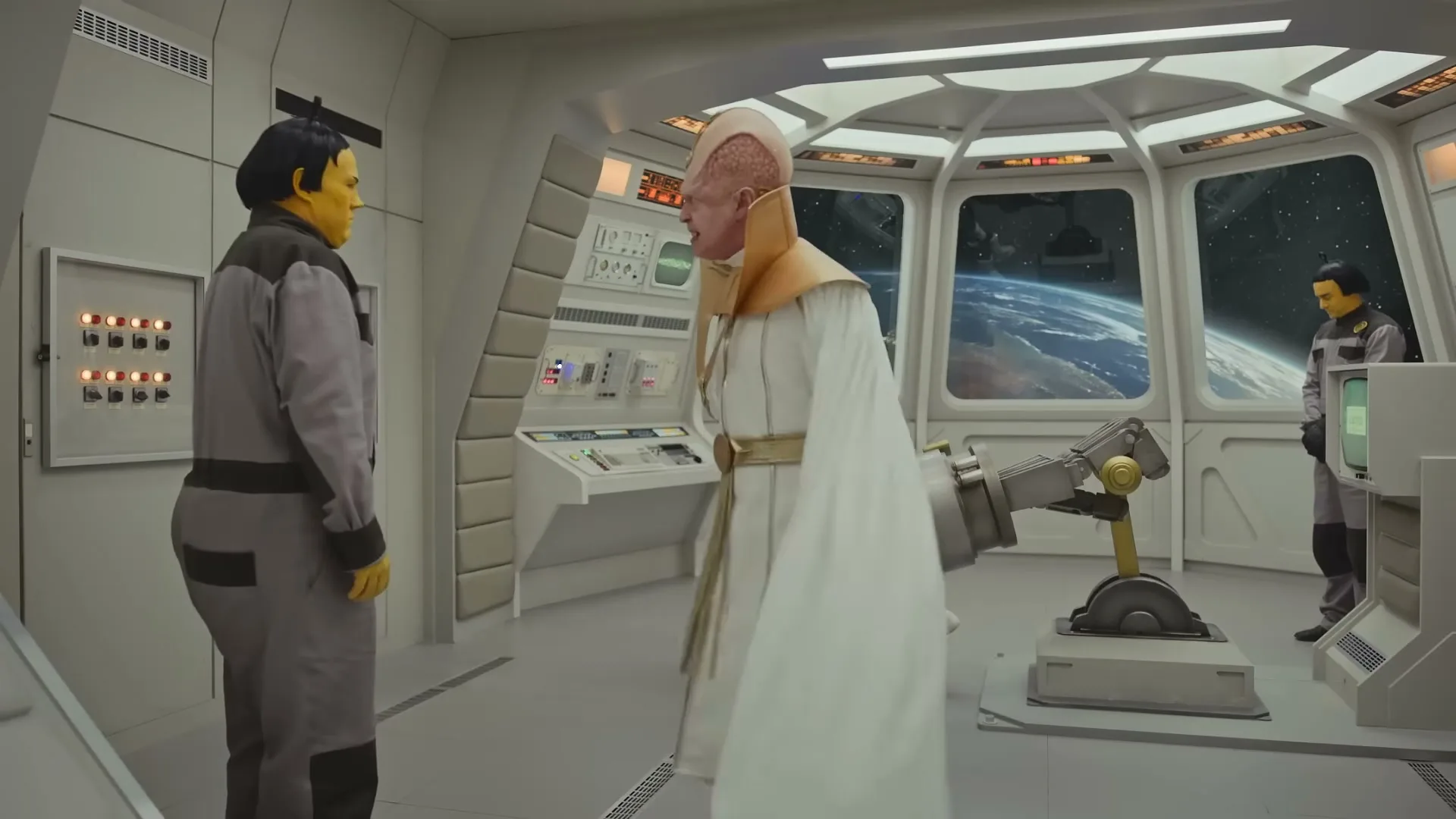 A man in a white robe and gold trim gestures emphatically at another man in a grey jumpsuit with yellow skin, inside a spaceship with views of Earth.