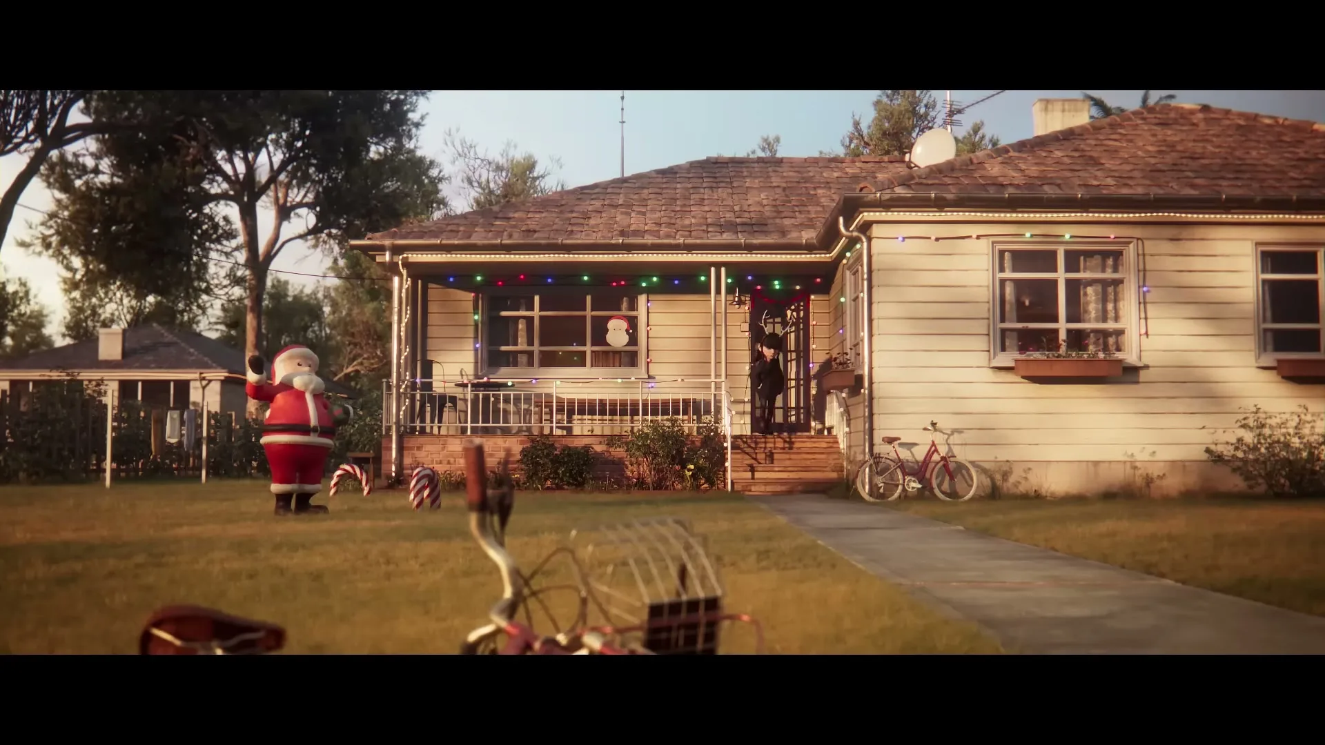 A wide shot of a suburban house decorated with Christmas lights and an inflatable Santa, with a child's bicycle in the foreground.