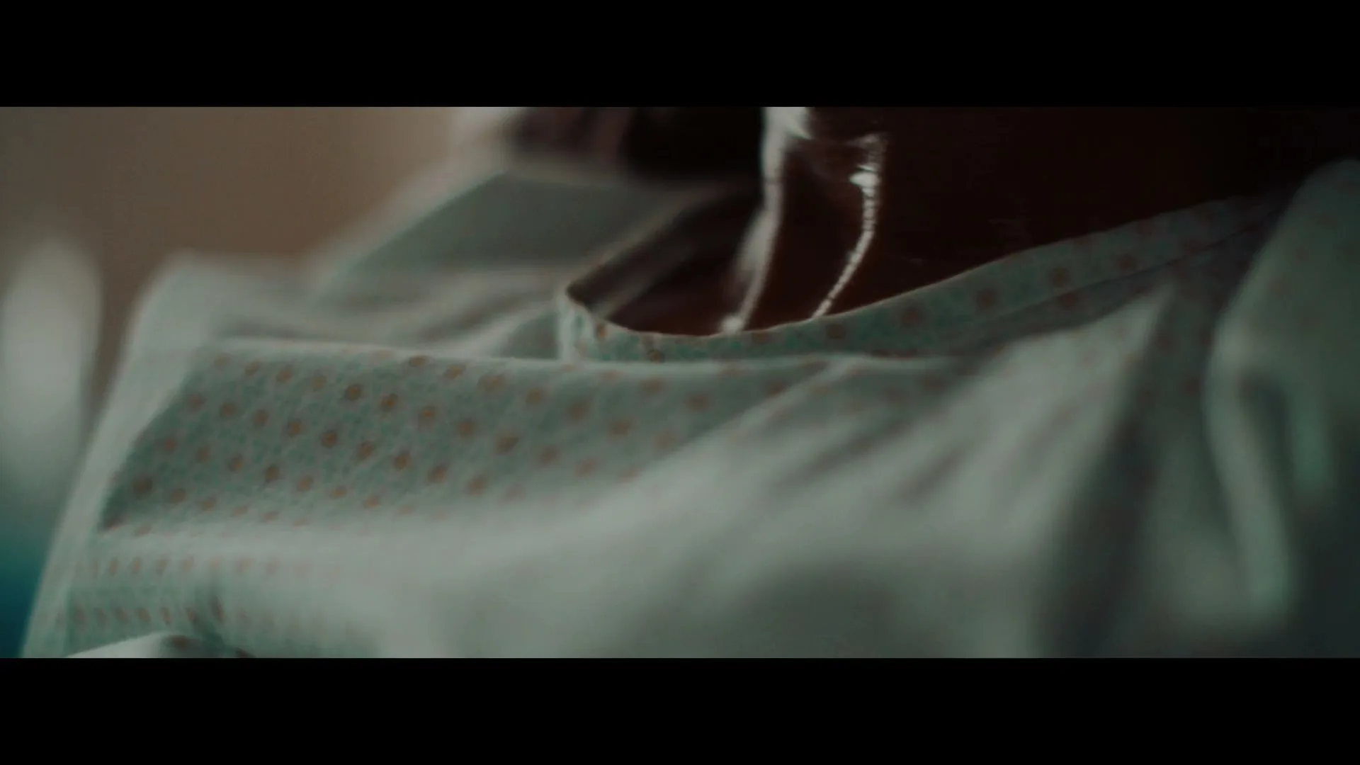 A person's chest and neck are visible, wearing a hospital gown, suggesting a medical setting.