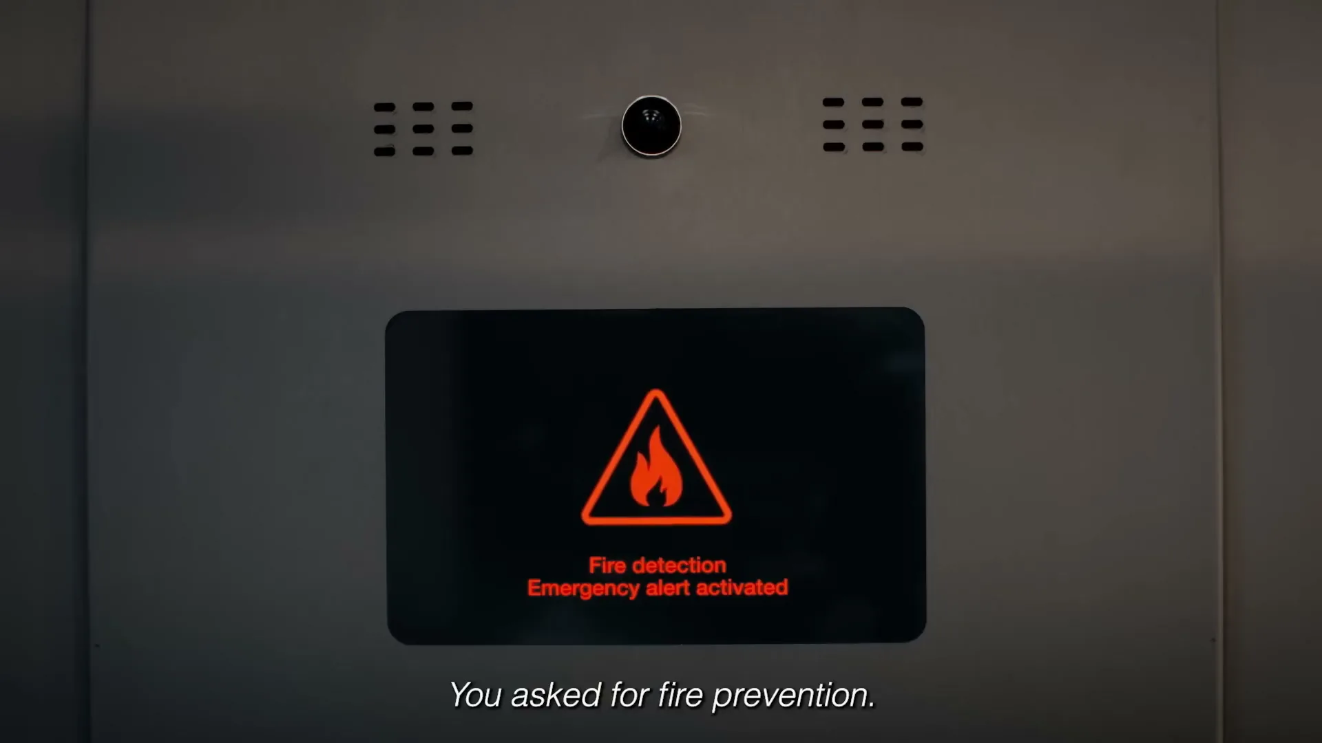 A close-up shot of an elevator control panel with a screen displaying a fire detection emergency alert.
