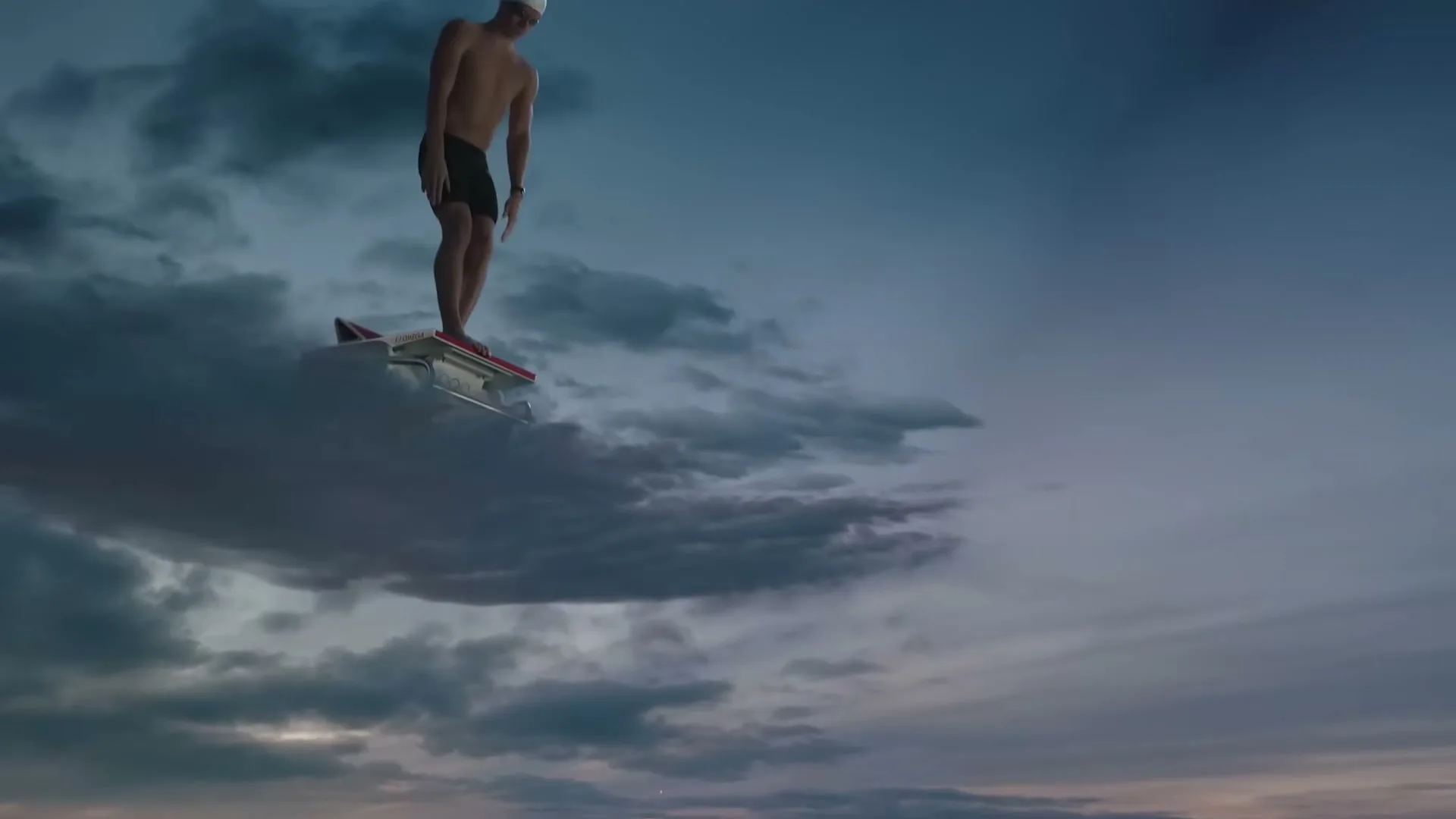 A male swimmer in a white cap and black trunks stands on a starting block made of clouds, preparing to dive into the sky above Paris at dusk.