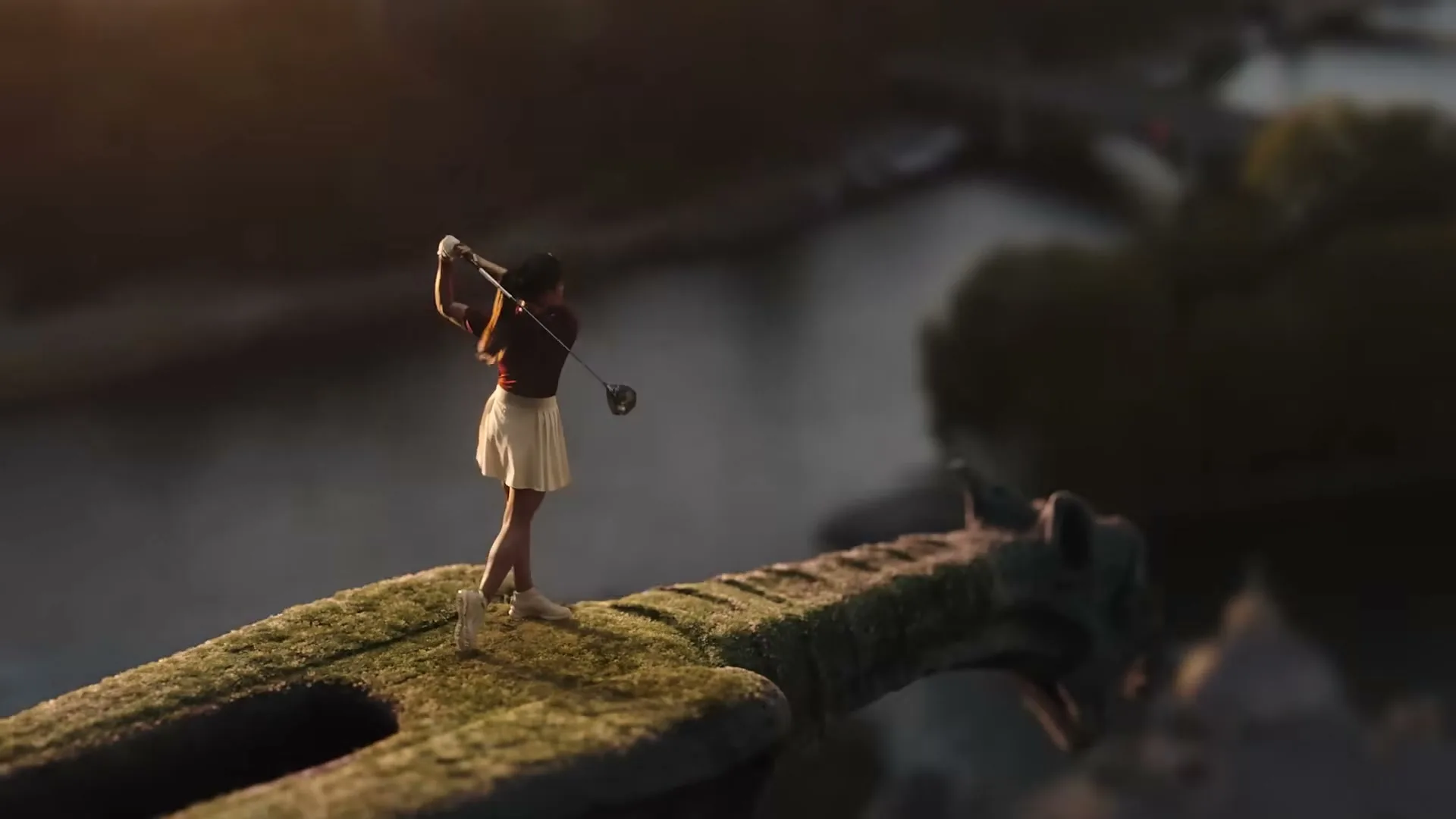 A female golfer in a red shirt and white skirt swings a golf club on a moss-covered gargoyle overlooking the Paris skyline at golden hour.
