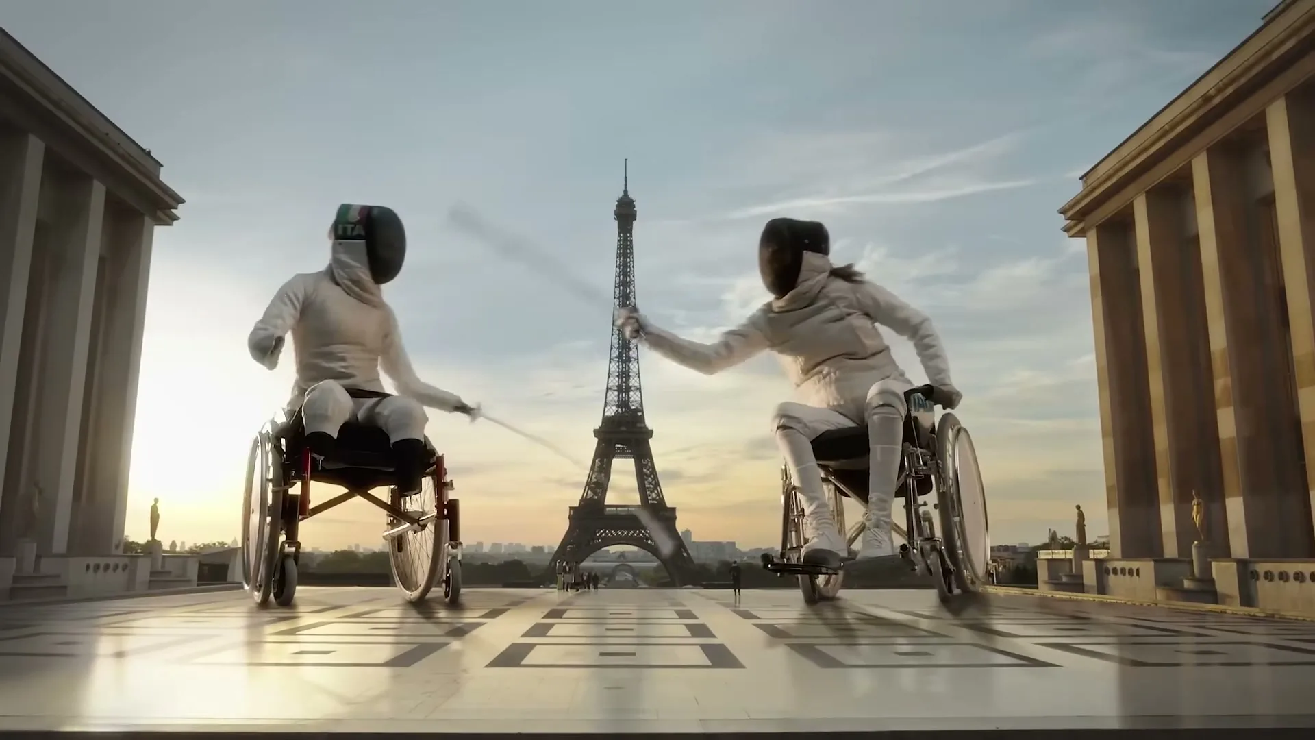 Two wheelchair fencers in white uniforms and masks duel in front of the Eiffel Tower at sunset, with classical buildings flanking them.