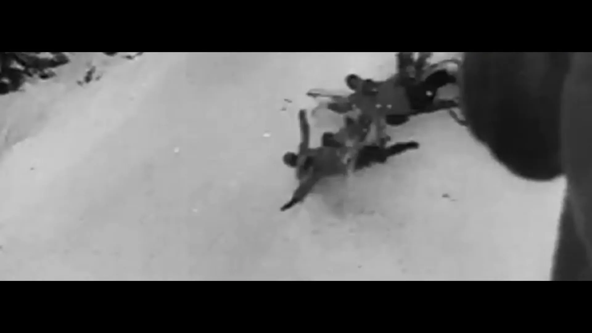A black and white archival shot shows a bobsled team crashing on a snowy track, with one person falling out of the sled.