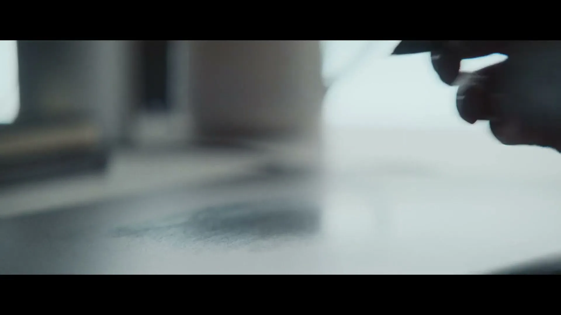 A person's hand, silhouetted, holds a pen and begins to write on a surface in an interior setting.
