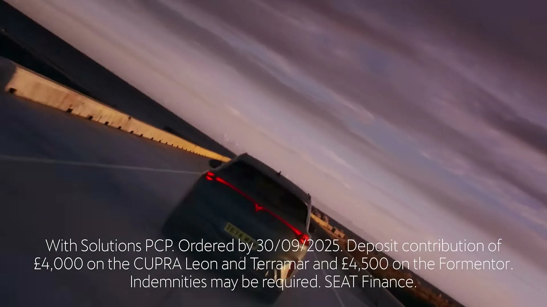A dark grey Cupra car drives on a highway at sunset, with legal disclaimer text overlaid on the screen.